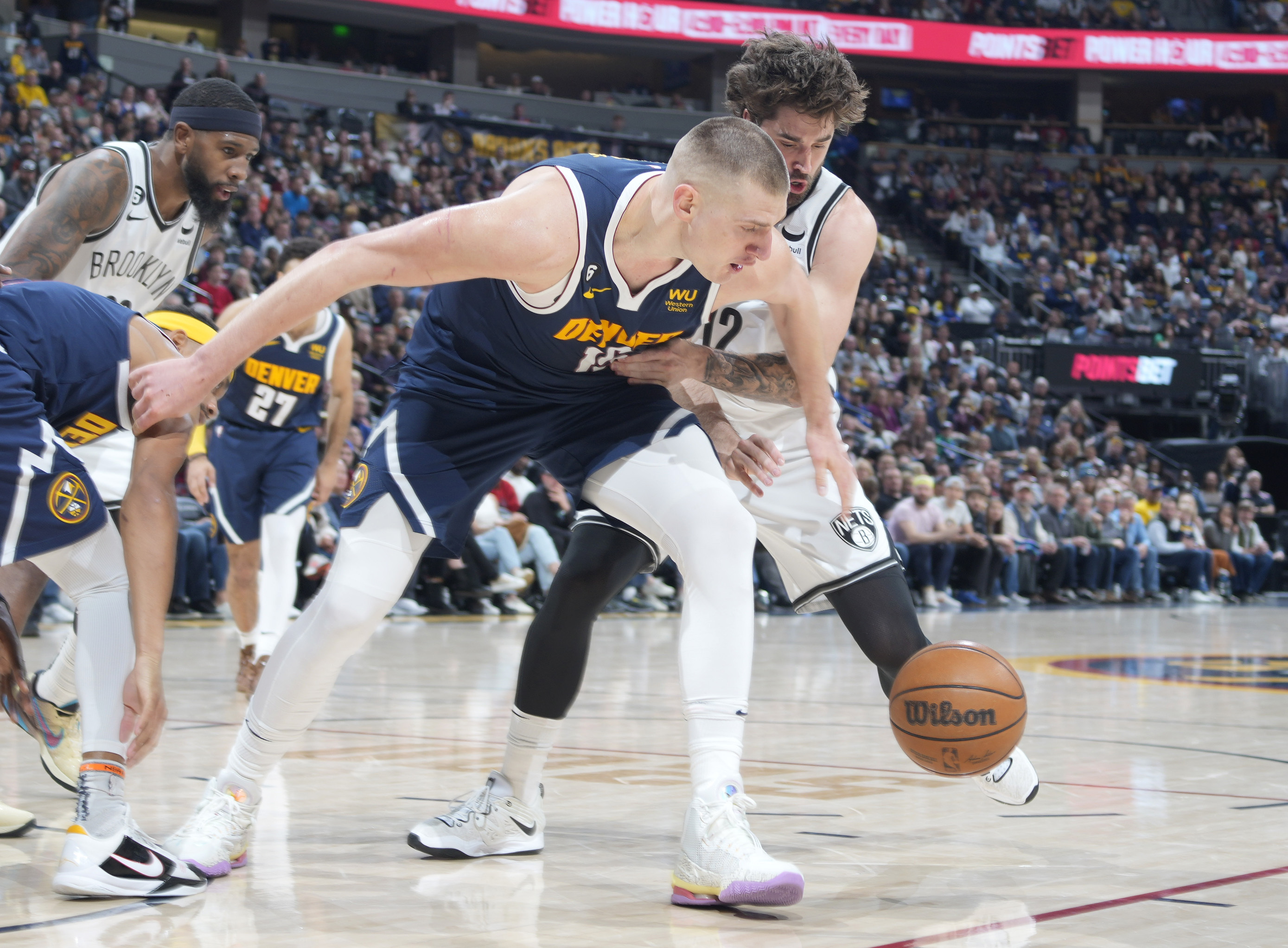 Denver Nuggets center Nikola Jokic, front, fights for control of the ball with Brooklyn Nets forward Joe Harris in the second half of an NBA basketball game Sunday, March 12, 2023, in Denver. (AP Photo/David Zalubowski)