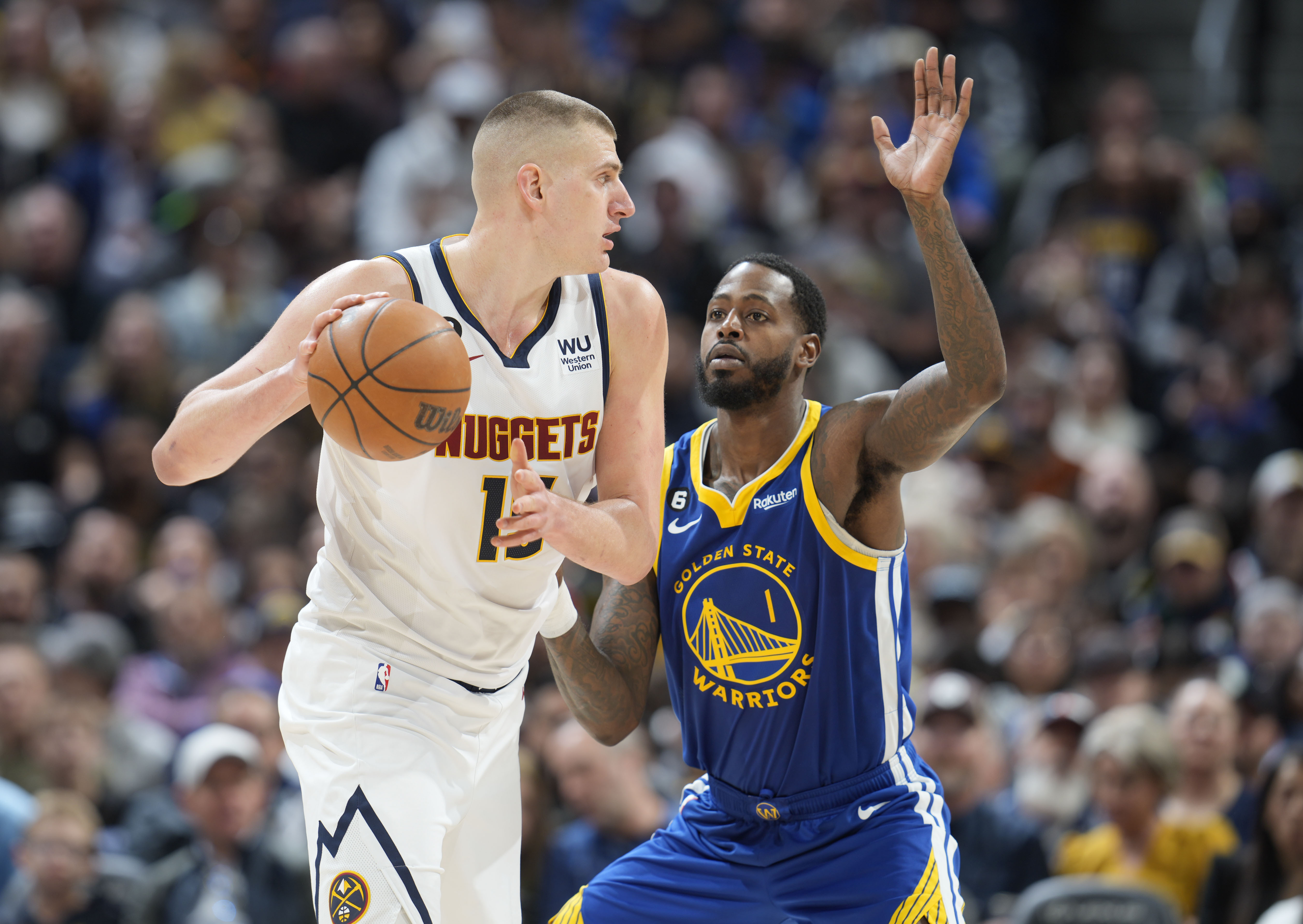 Denver Nuggets center Nikola Jokic, left, looks to pass the ball as Golden State Warriors forward JaMychal Green defends in the second half of an NBA basketball game Thursday, Feb. 2, 2023, in Denver. (AP Photo/David Zalubowski)
