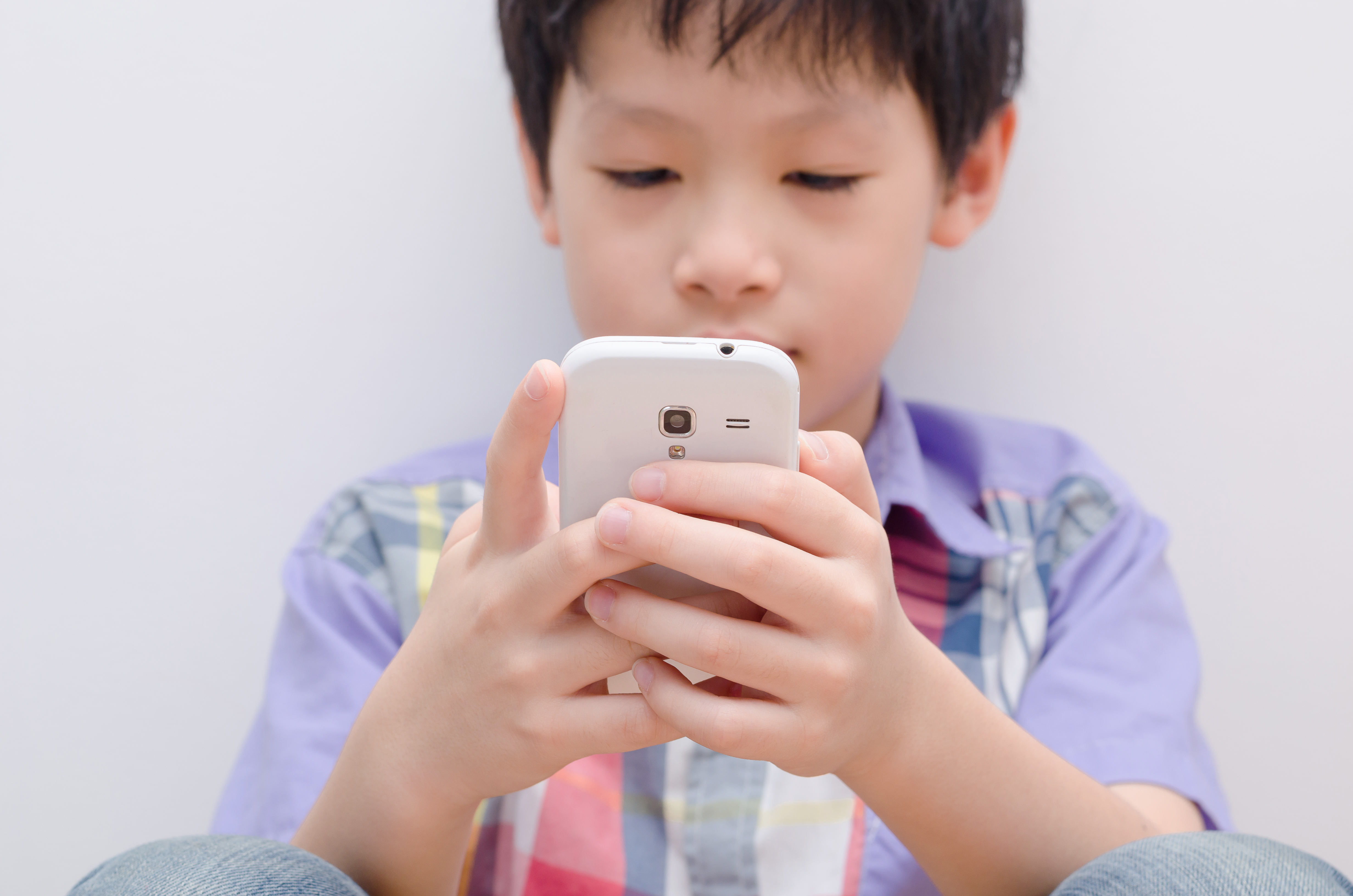 Young,Asian,Boy,Play,Game,On,Smart,Phone,focus,At,Hand