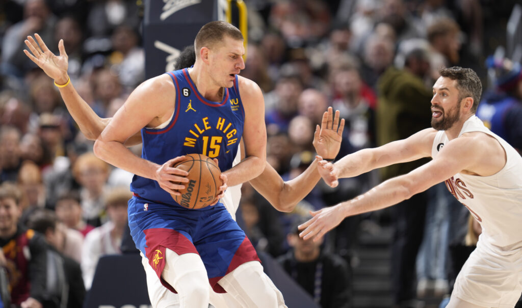 Denver Nuggets center Nikola Jokic, front left, is caught with the ball by Cleveland Cavaliers center Jarrett Allen, back left, and forward Kevin Love in the first half of an NBA basketball game Friday, Jan. 6, 2023, in Denver. (AP Photo/David Zalubowski)