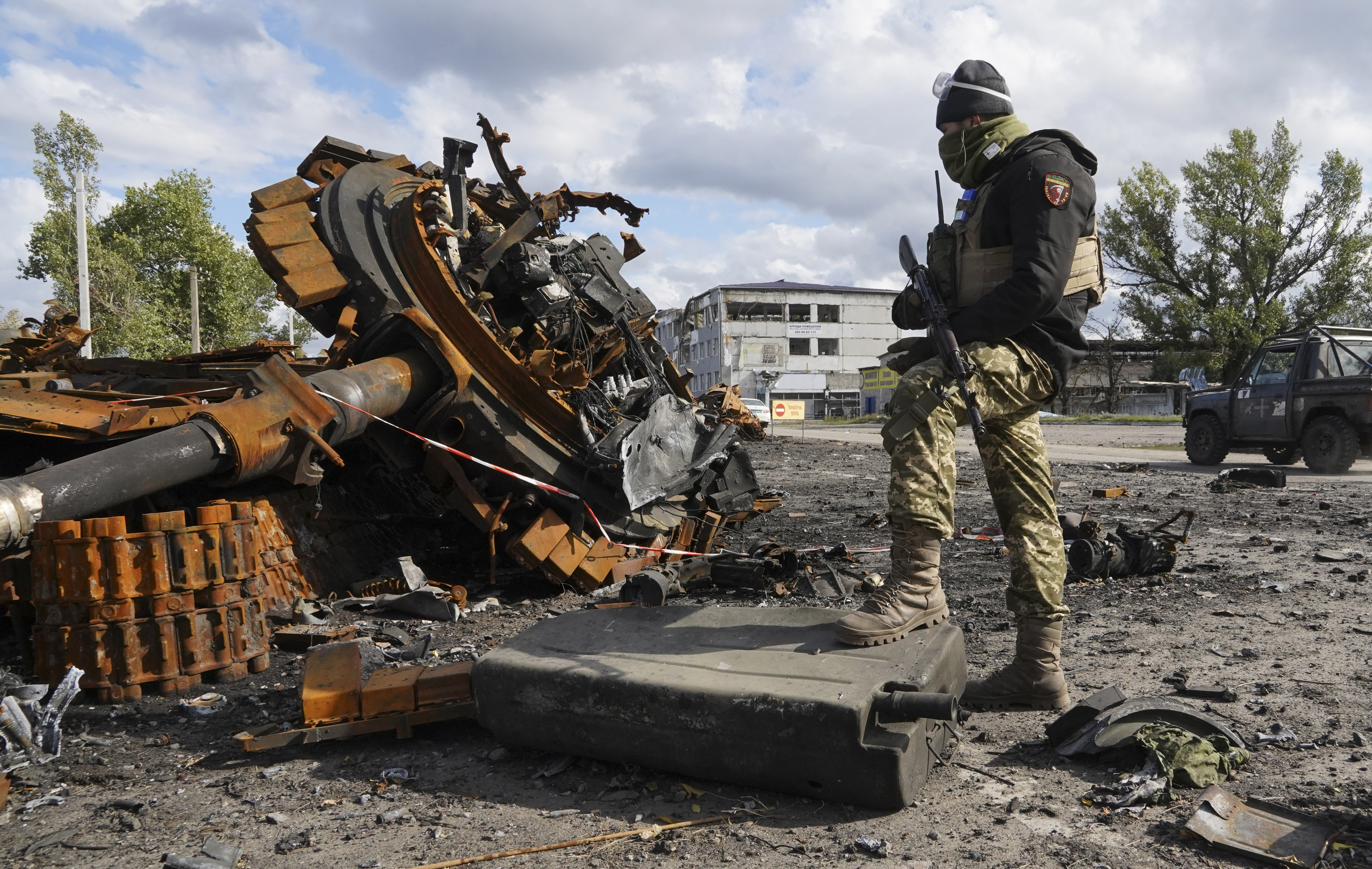A Ukrainian soldier stands near a damaged Russian tank in Kupyansk in the Kharkiv region, Ukraine, Tuesday, Oct. 4, 2022. (AP Photo/Andrii Marienko)
