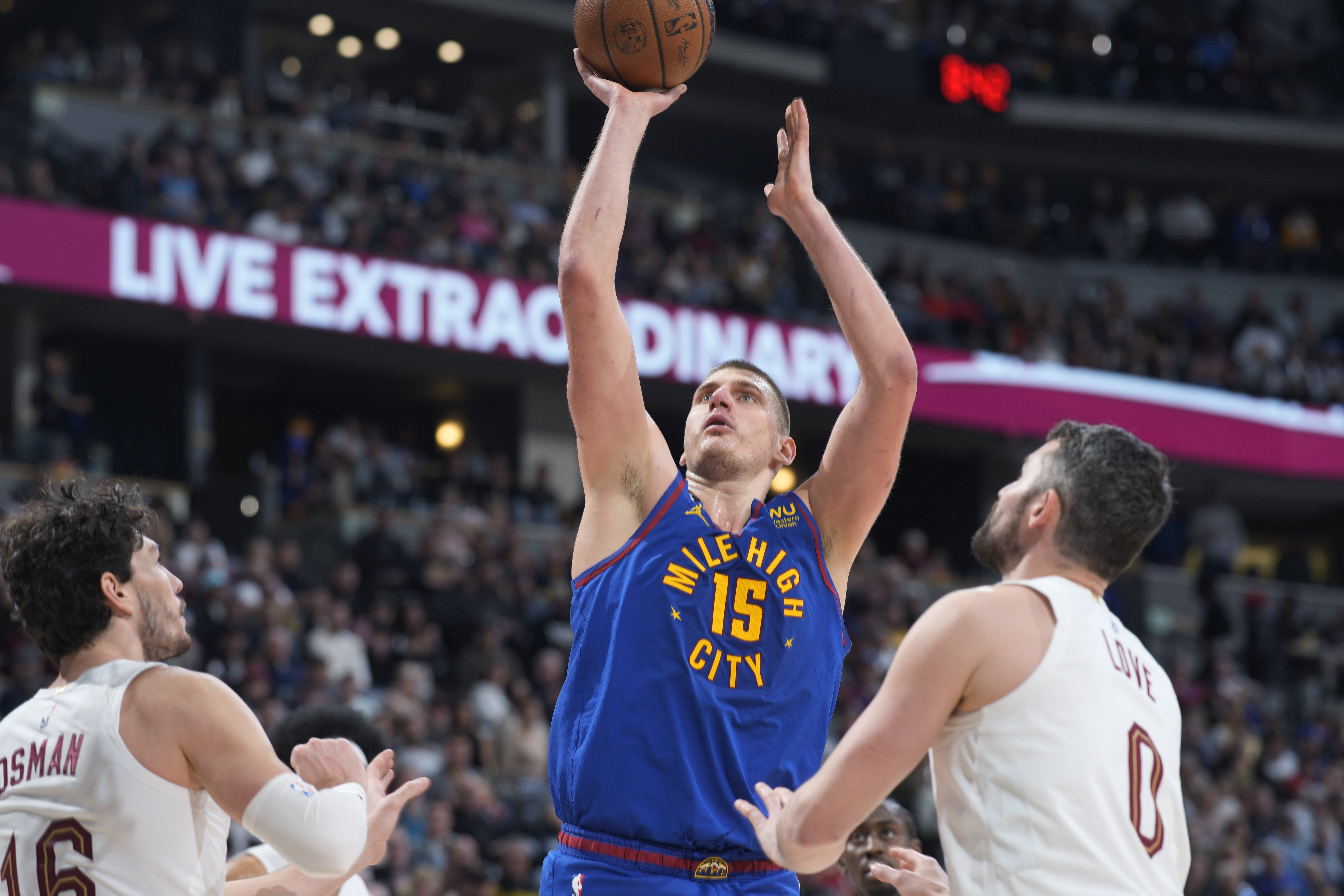 Denver Nuggets center Nikola Jokic shoots between Cleveland Cavaliers forward Cedi Osman, left, and forward Kevin Love during the second half of an NBA basketball game Friday, Jan. 6, 2023, in Denver. (AP Photo/David Zalubowski)