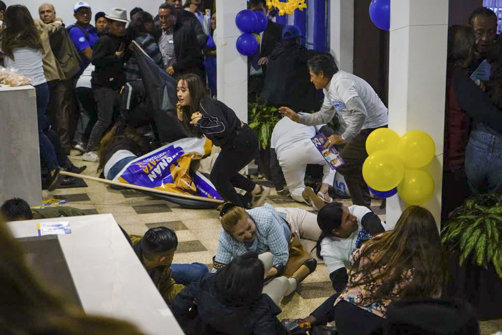 Supporters of presidential candidate Fernando Villavicencio run for cover after he was shot to death while at a campaign rally outside a school in Quito, Ecuador, Wednesday, Aug. 9, 2023. (API via AP)