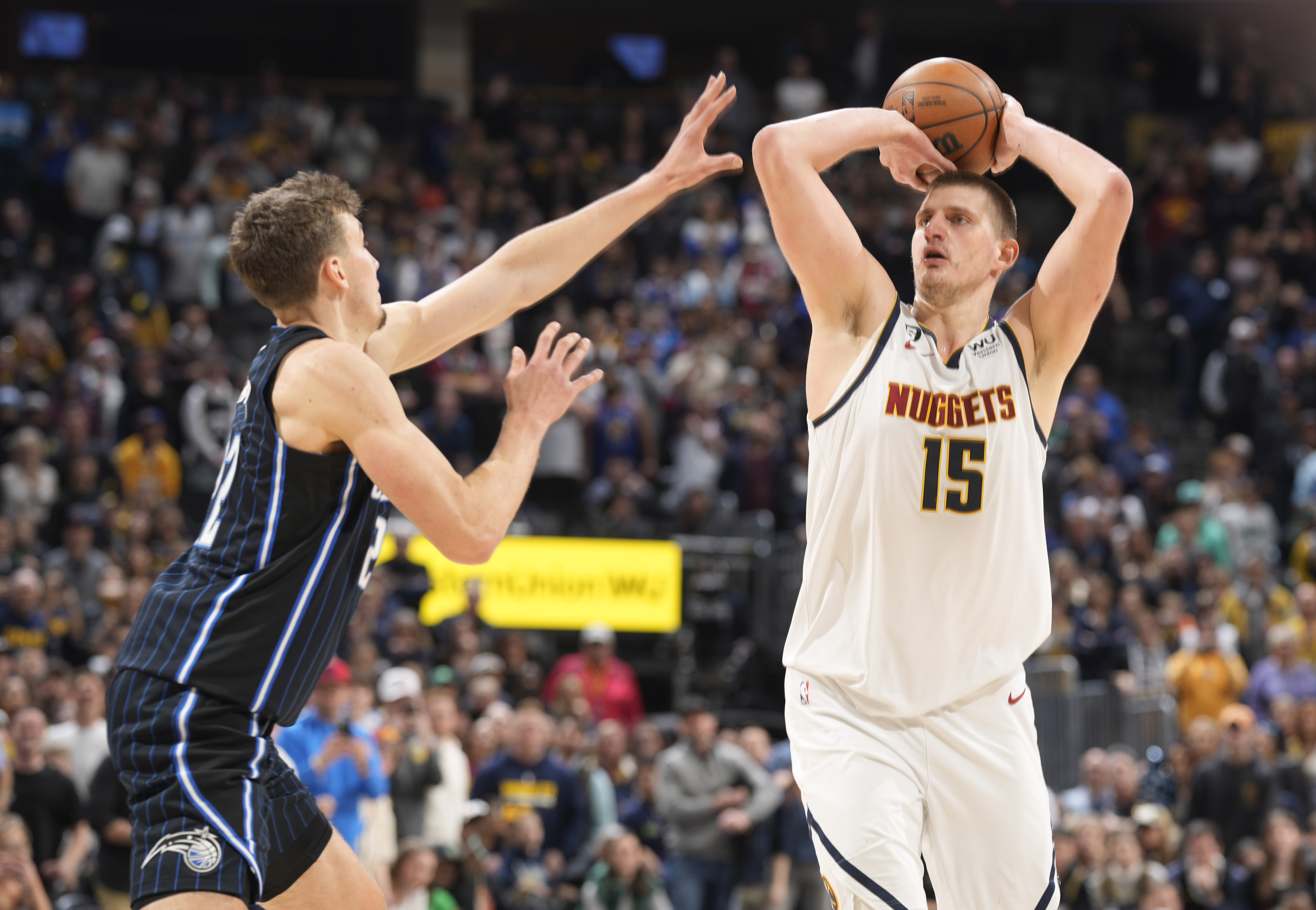 Denver Nuggets center Nikola Jokic, right, shoots a winning 3-point basket over Orlando Magic forward Franz Wagner late in the second half of an NBA basketball game Sunday, Jan. 15, 2023, in Denver. (AP Photo/David Zalubowski)