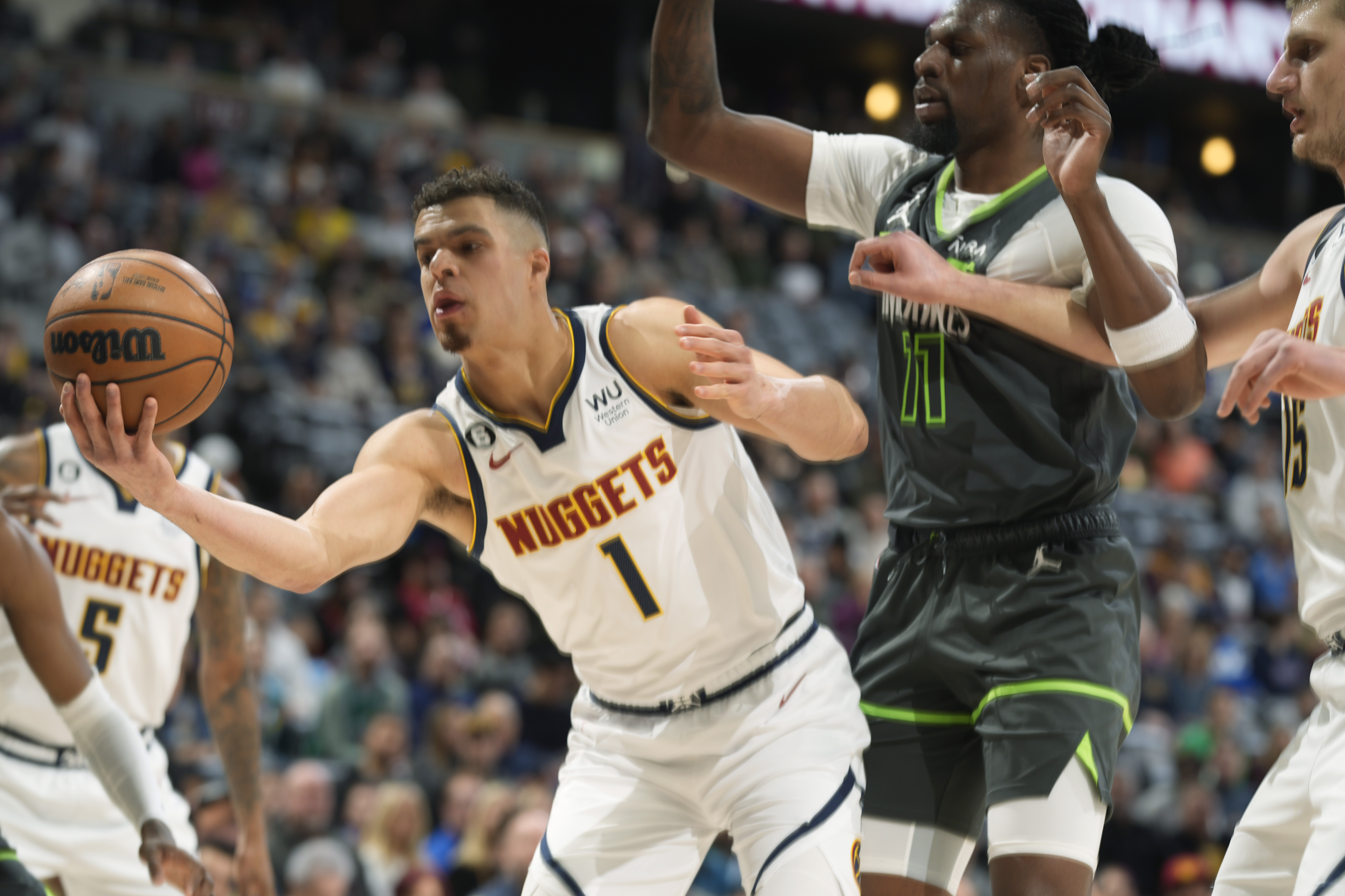 Denver Nuggets forward Michael Porter Jr., left, pulls in a loose ball as Minnesota Timberwolves center Naz Reid defends in the first half of an NBA basketball game Wednesday, Jan. 18, 2023, in Denver. (AP Photo/David Zalubowski)