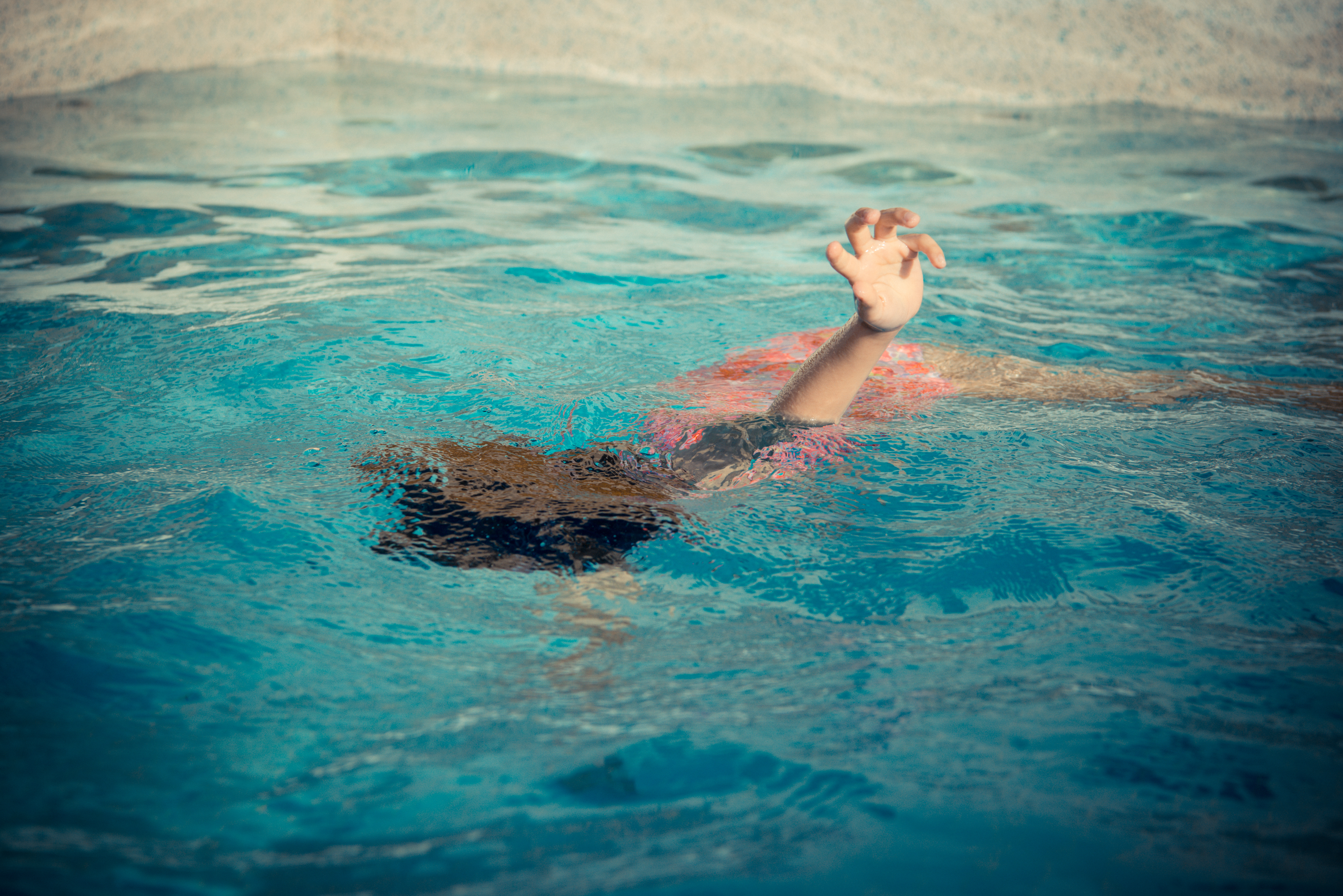 Young,Little,Girl,Floating,At,Swimming,Pool,And,Showing,Hand