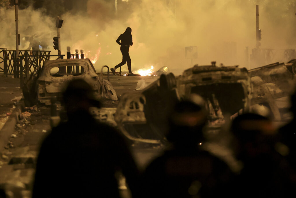 A demonstrator runs on the third night of protests sparked by the fatal police shooting of a 17-year-old driver in the Paris suburb of Nanterre, France, Friday, June 30, 2023. (AP Photo/Aurelien Morissard)