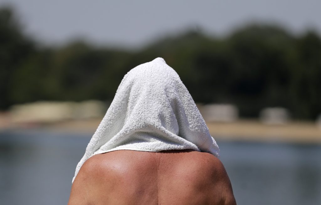 epa10086027 A man covers his head with a towel at the Ada Ciganlija lake in Belgrade, Serbia, 22 July 2022. Serbia's Hydrometeorological Service issued a warning on high temperatures of over 40 degrees Celsius in the following days.  EPA-EFE/ANDREJ CUKIC