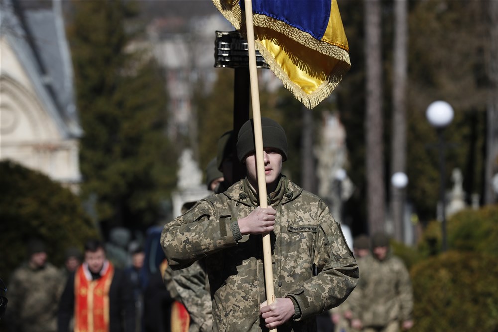 epa09831058 Soldiers carry a Ukrainian national flag during the funeral of Ukrainian army officer Ivan Skrypnyk, killed in action on 13 March, in Lviv, Ukraine, 17 March 2022, as the Russian invasion of Ukraine enters its fourth week.  EPA-EFE/ATEF SAFADI