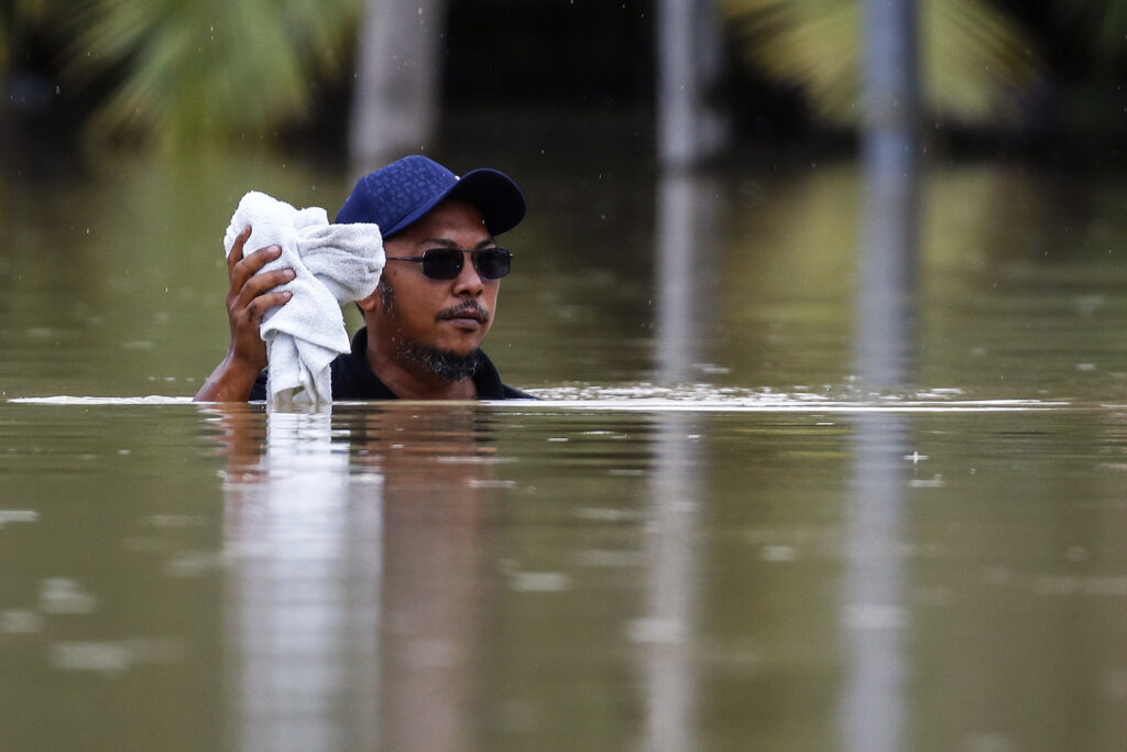 epa10501875 A man wades through a flooded area while raining in Yong Peng, Johor, Malaysia, 04 March 2023. According to state media, more than 33,000 people were evacuated in four states affected by the floods.  EPA-EFE/FAZRY ISMAIL