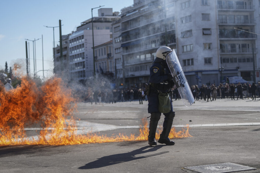Riot police try to avoid the flames of a molotov cocktail thrown by protesters during a protest for victims of a rail disaster, outside of the Parliament in central Athens, on Wednesday, March 8, 2023.  (AP Photo/Petros Giannakouris)