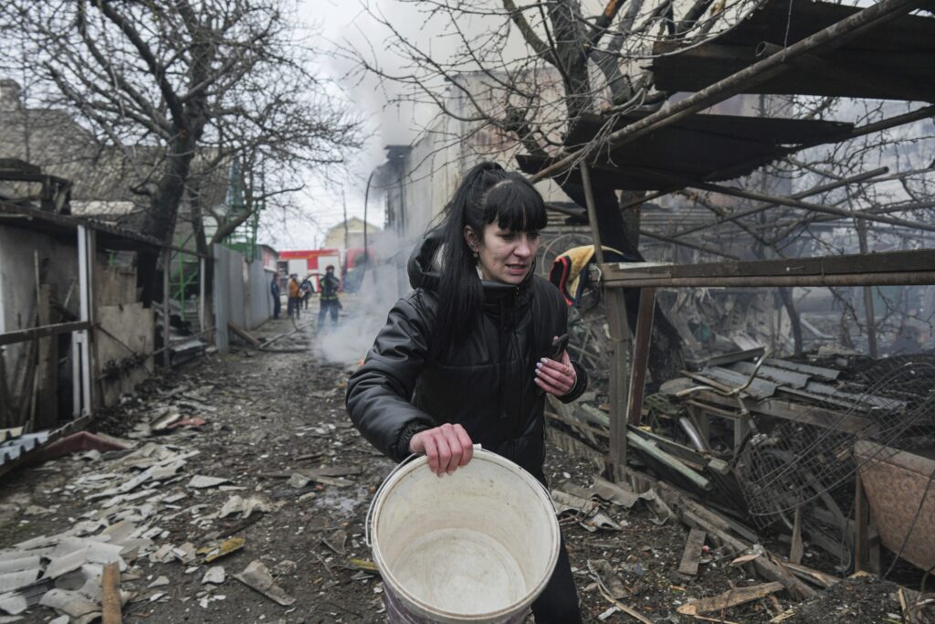 FILE - A woman walks past the debris in the aftermath of Russian shelling, in Mariupol, Ukraine, Thursday, Feb. 24, 2022. (AP Photo/Evgeniy Maloletka, File)
