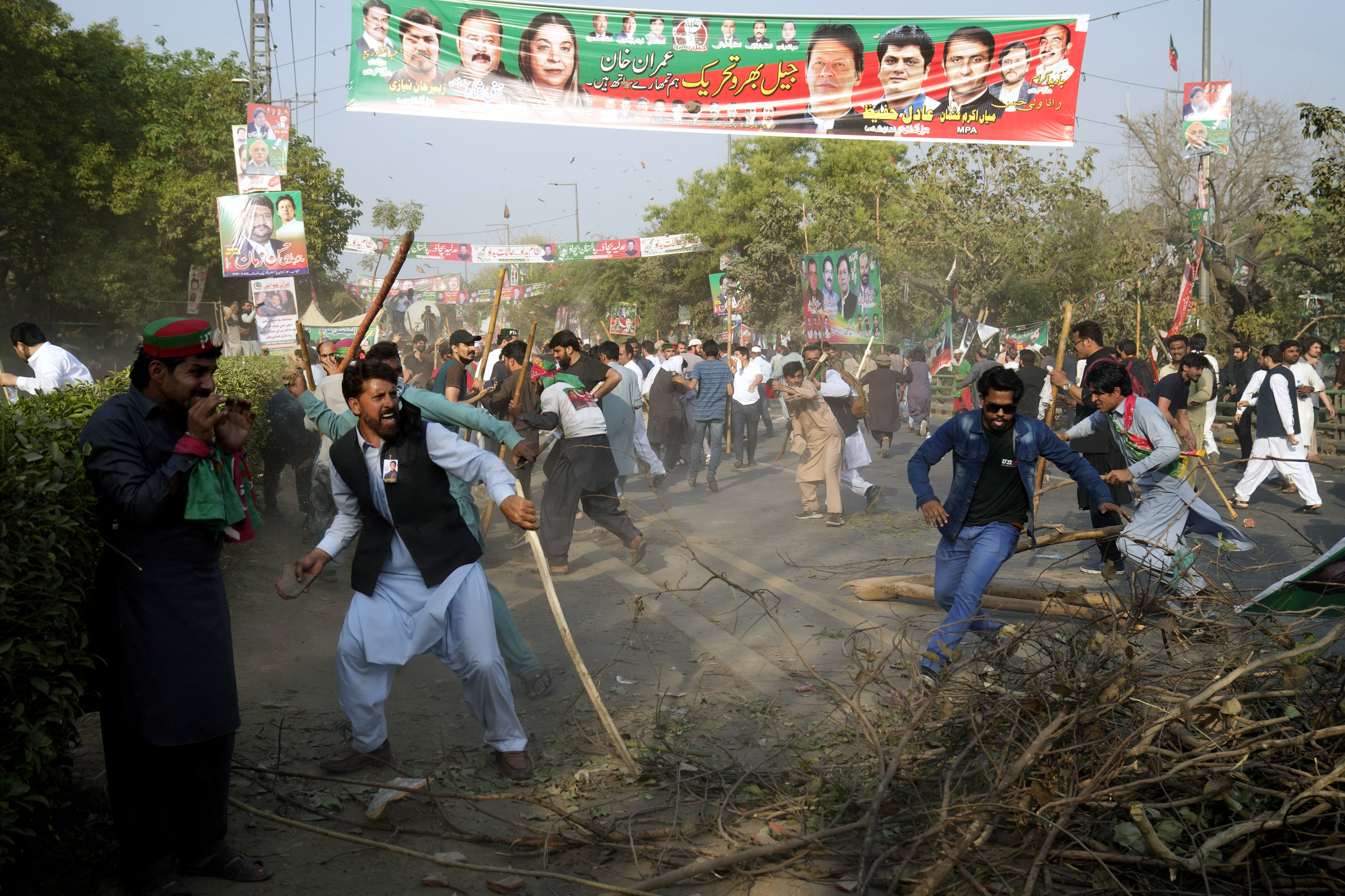 Supporters of former Prime Minister Imran Khan throw stones toward riot police officers during clashes outside Khan's residence, in Lahore, Pakistan, Tuesday, March 14, 2023. (AP Photo/K.M. Chaudary)