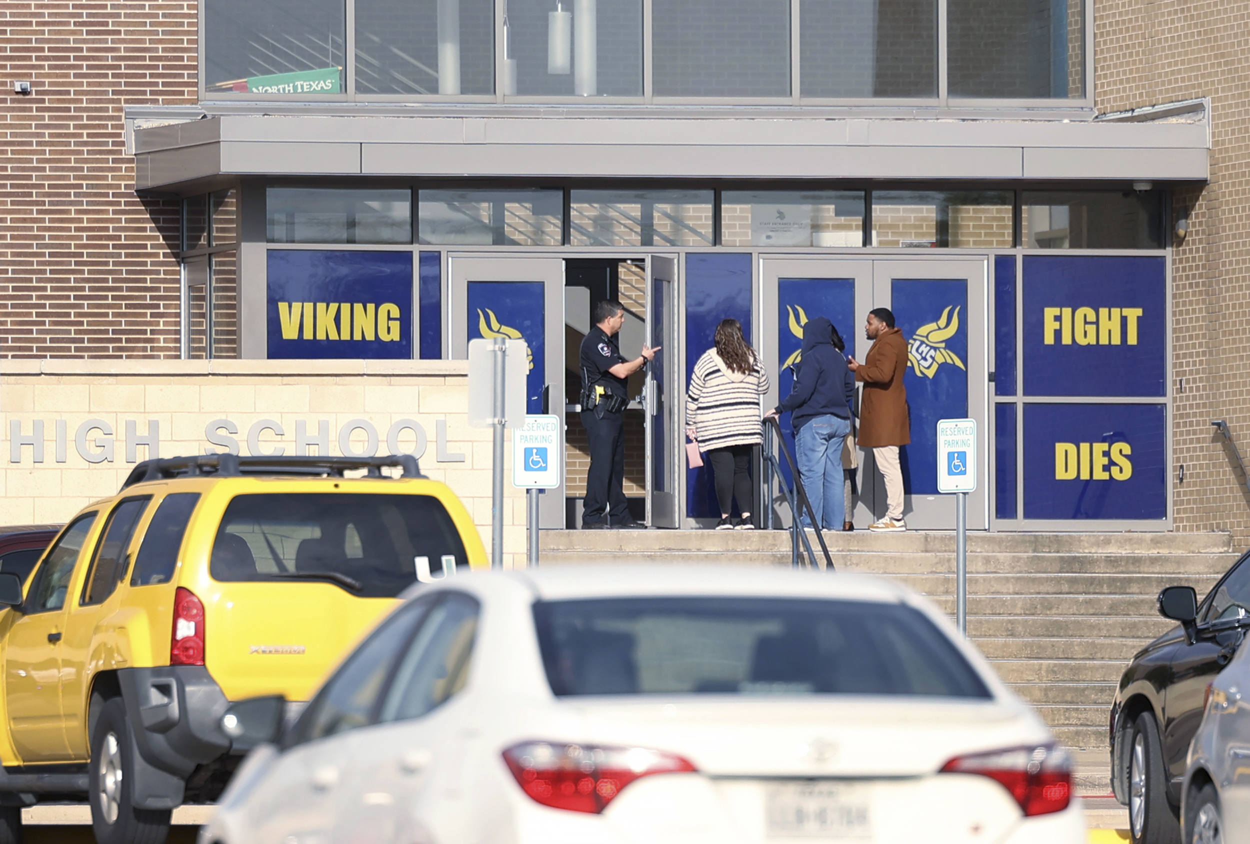 An Arlington police officer speaks to individuals outside of Lamar High School in Arlington during a lockdown after a shooting on Monday, March 20, 2023. (Amanda McCoy/Fort Worth Star-Telegram)