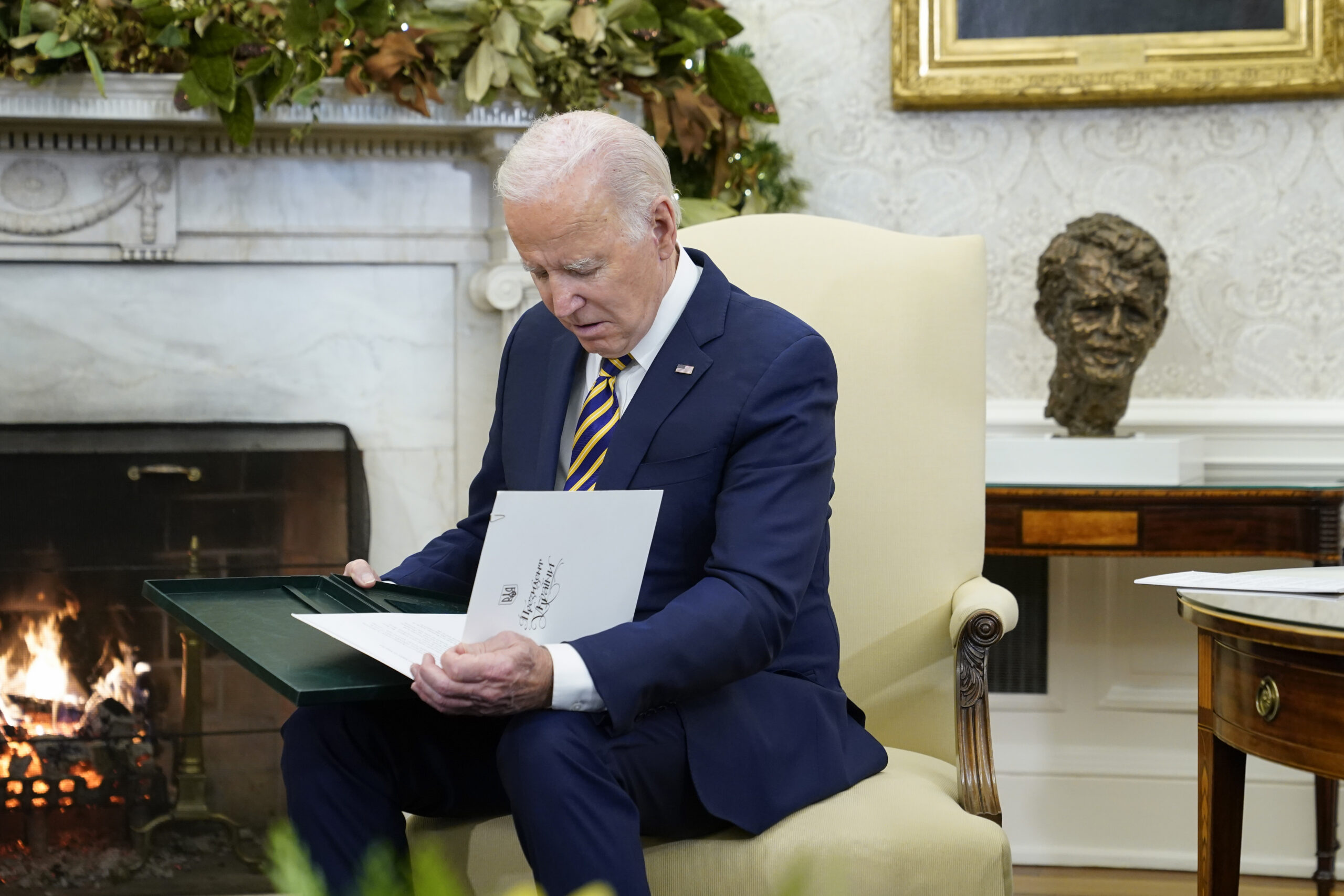 President Joe Biden holds a gift he received from Ukrainian President Volodymyr Zelenskyy as they meet in the Oval Office of the White House, Wednesday, Dec. 21, 2022, in Washington. (AP Photo/Patrick Semansky)