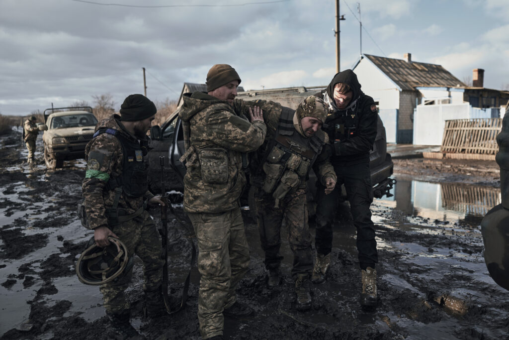 Ukrainian soldiers help a wounded comrade into an evacuation vehicle in the frontline in Bakhmut, Donetsk region, Ukraine, Monday, Feb. 20, 2023. (AP Photo/Libkos)