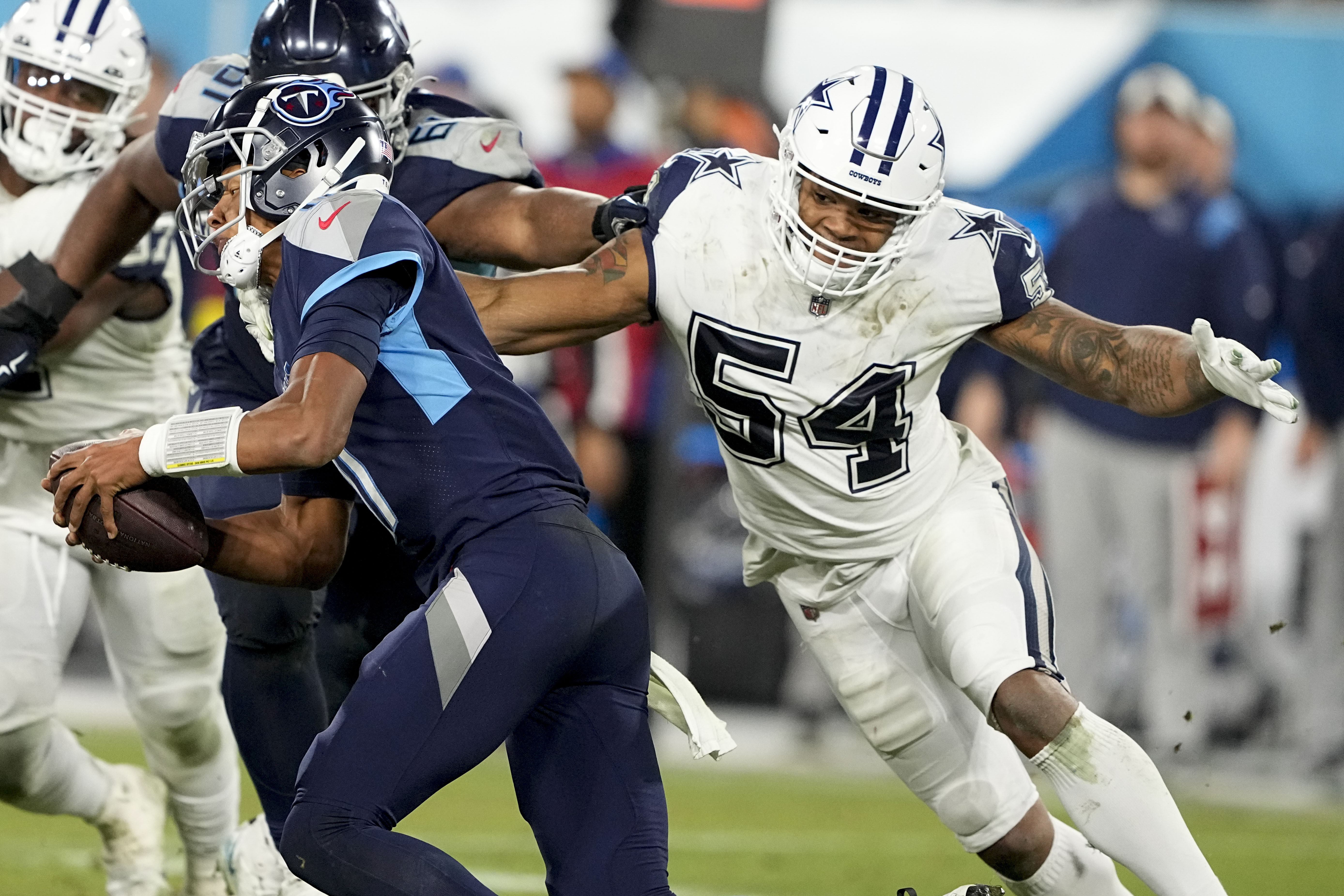Tennessee Titans quarterback Joshua Dobbs (11) runs away from Dallas Cowboys defensive end Sam Williams (54) during the second half of an NFL football game, Thursday, Dec. 29, 2022, in Nashville, Tenn. (AP Photo/Chris Carlson)