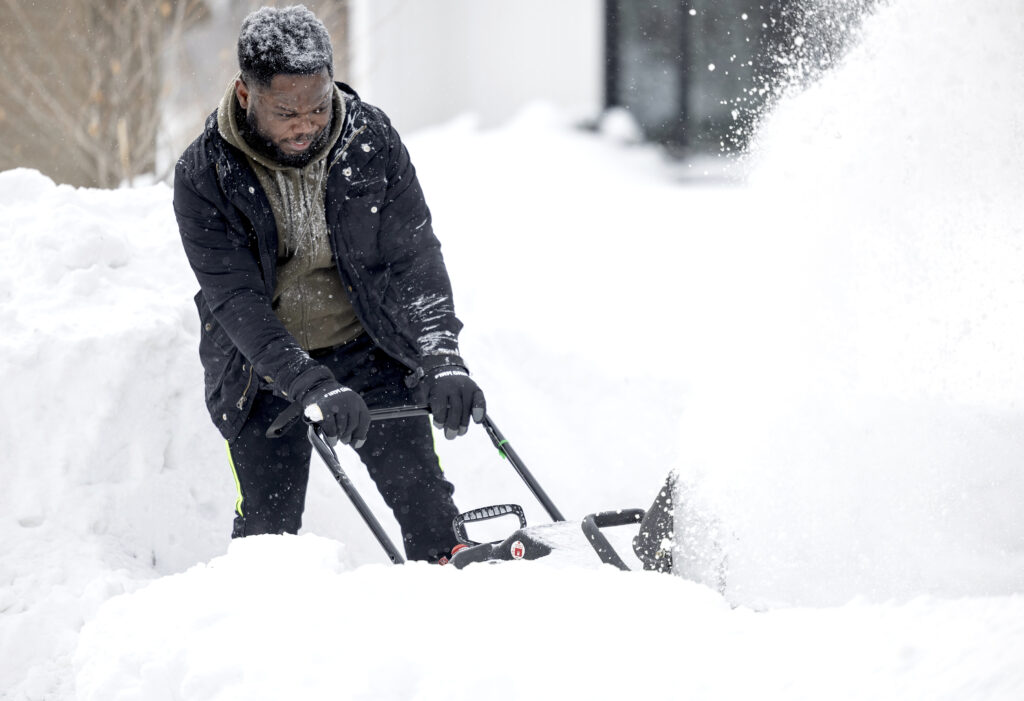 Princewill Eneh clears his driveway with a snowblower Thursday, Feb. 23, 2022, in Eden Prairie, Minn. (Carlos Gonzalez/Star Tribune via AP)
