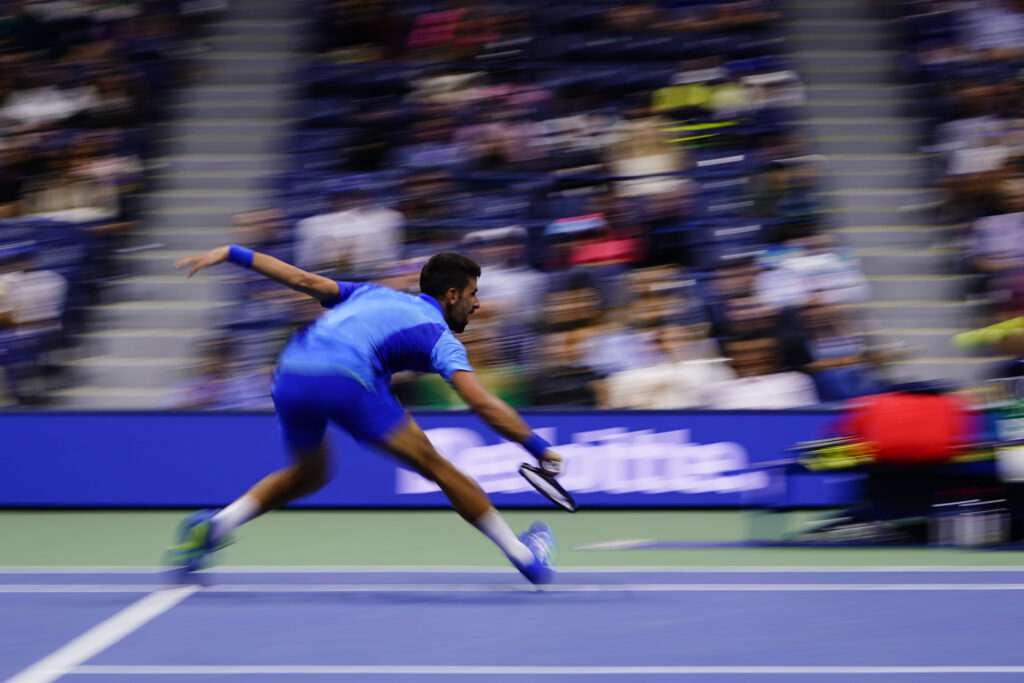 In this image made with a slow shutter speed, Novak Djokovic, of Serbia, returns a shot to Laslo Djere, of Serbia, during the third round of the U.S. Open tennis championships, Saturday, Sept. 2, 2023, in New York. (AP Photo/Frank Franklin II)