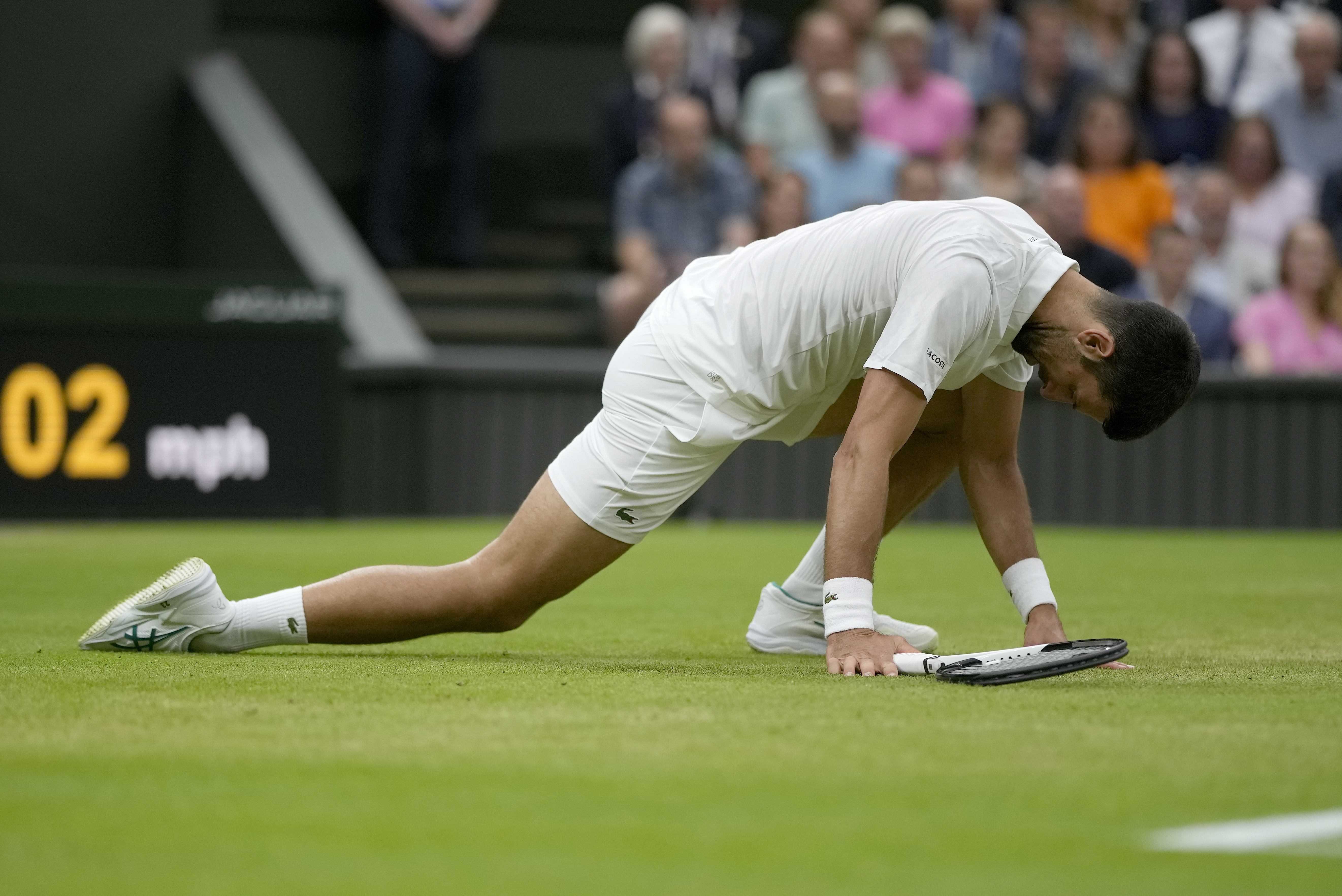 Serbia's Novak Djokovic slips on the court as he returns to Italy's Jannik Sinner in a men's singles semifinal match on day twelve of the Wimbledon tennis championships in London, Friday, July 14, 2023. (AP Photo/Alastair Grant)