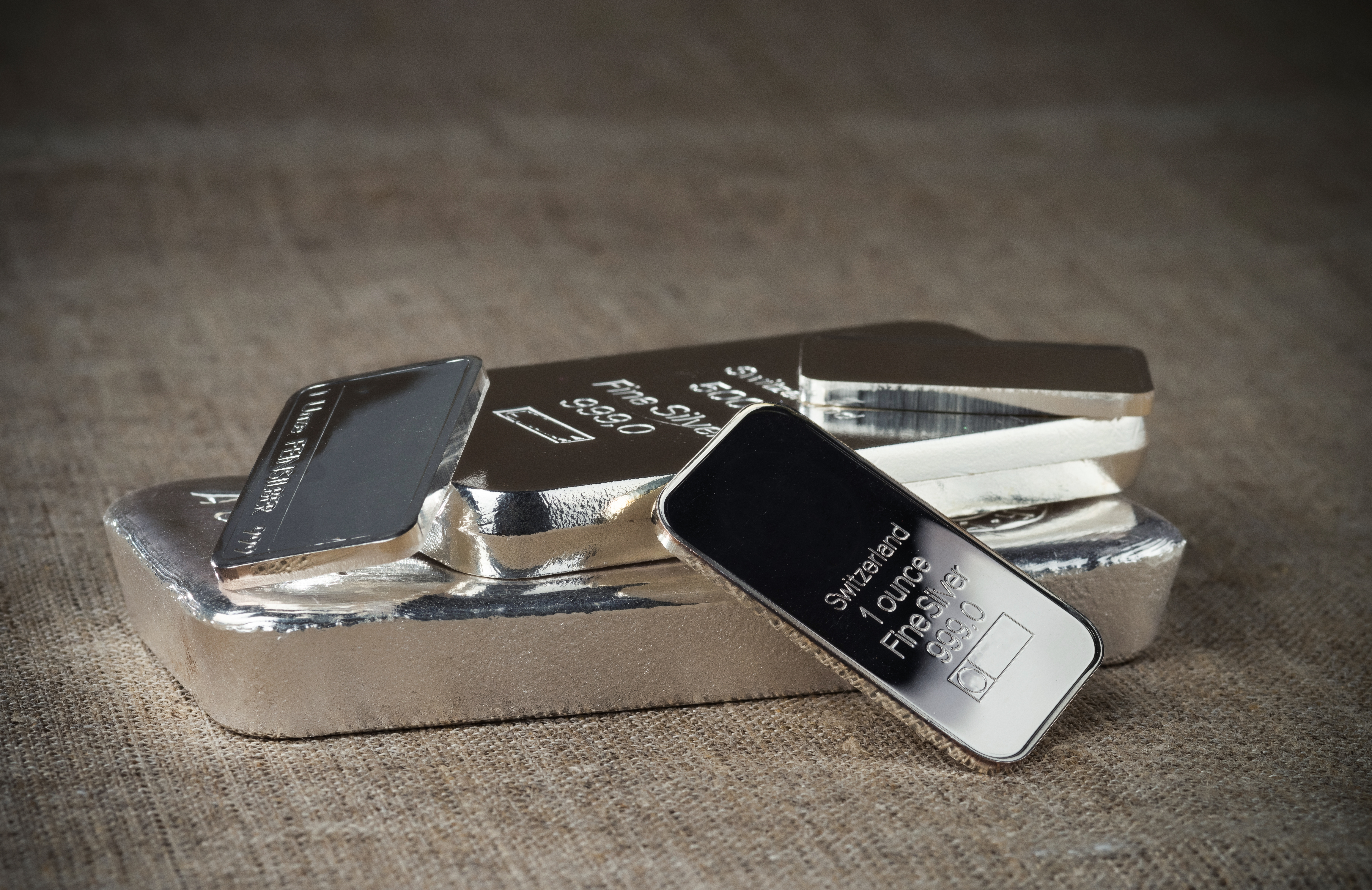 Several,Silver,Bars,Of,Various,Weights,On,A,Textile,Texture