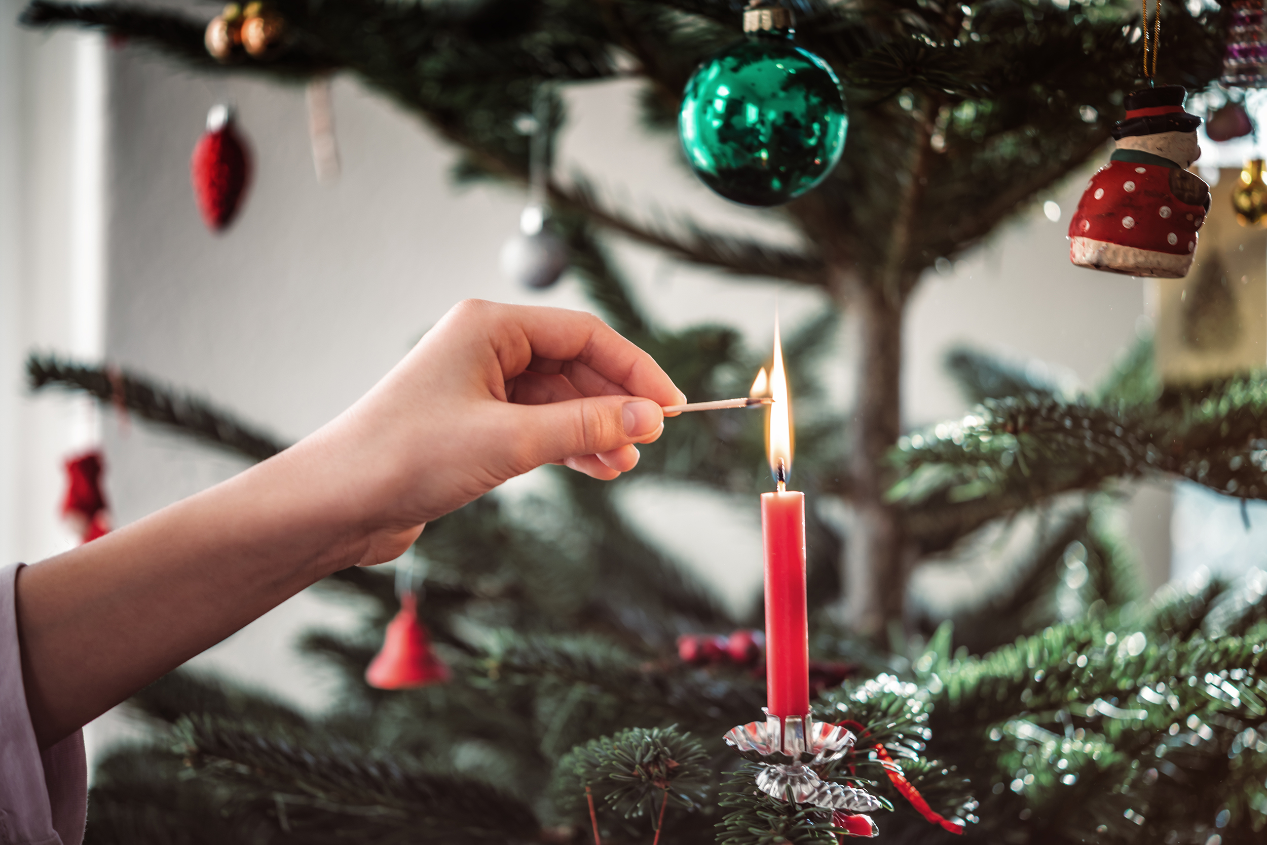 Female,Hand,Lighting,Candle,On,Christmas,Tree