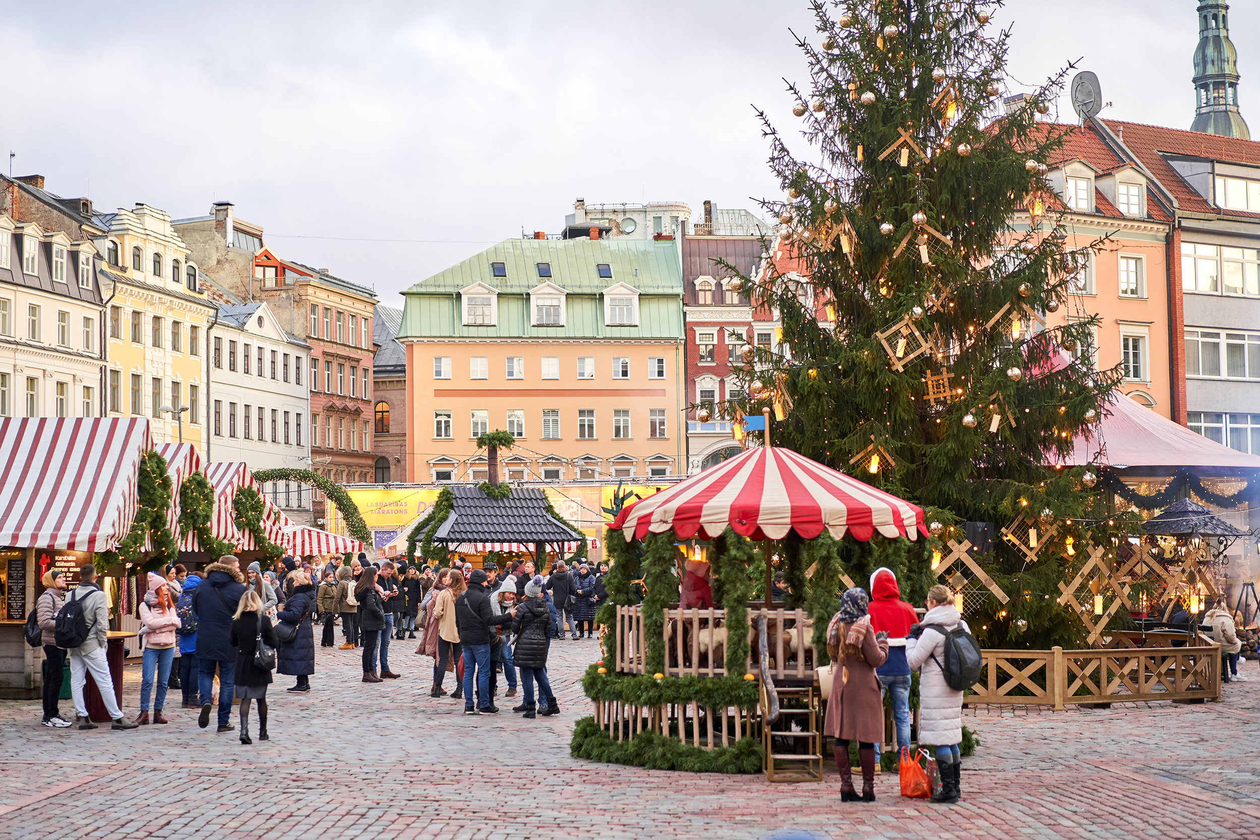 Riga, Latvia - December 09 2019. Christmas market on Dome Square, in the Old Town. People buying traditional souvenirs at a European Christmas market. Trading houses with sale of christmas gifts.