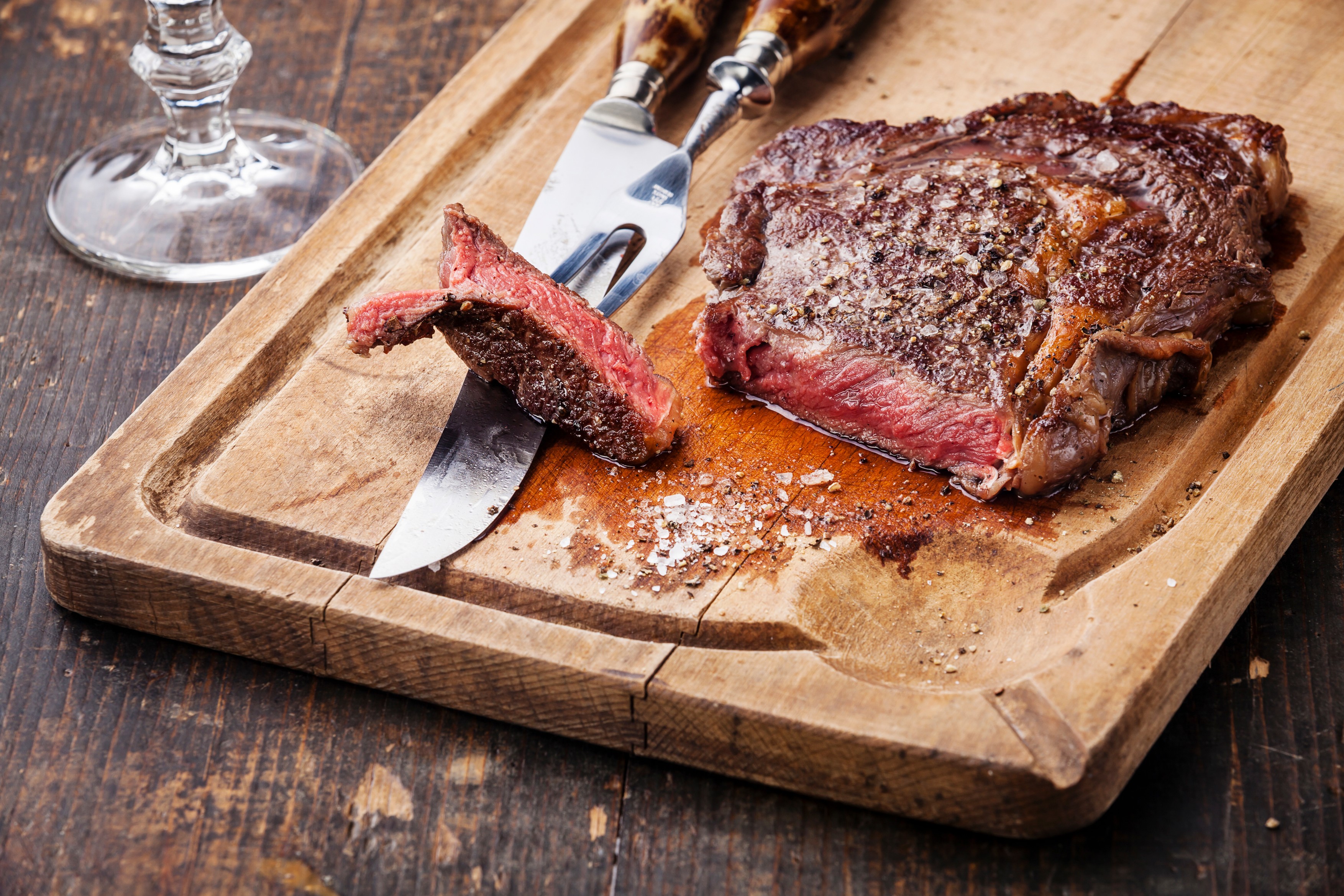 Steak Ribeye with knife and fork for meat on cutting board on dark wooden background,Image: 725288326, License: Royalty-free, Restrictions: , Model Release: no, Credit line: Lisovskaya Natalia / The Picture Pantry / Profimedia