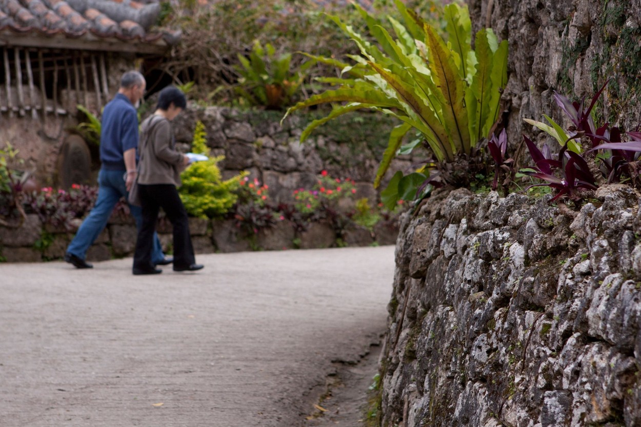 An elderly Japanese couple walk through the grounds of Ryukyu Mura on the main island of Okinawa, Japan