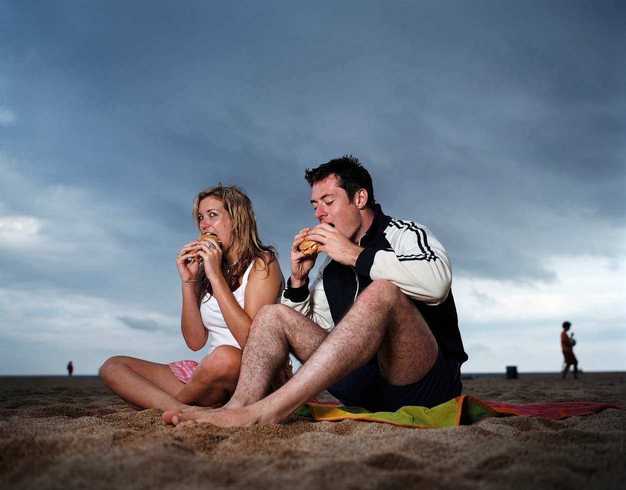 Couple eating hamburgers on beach