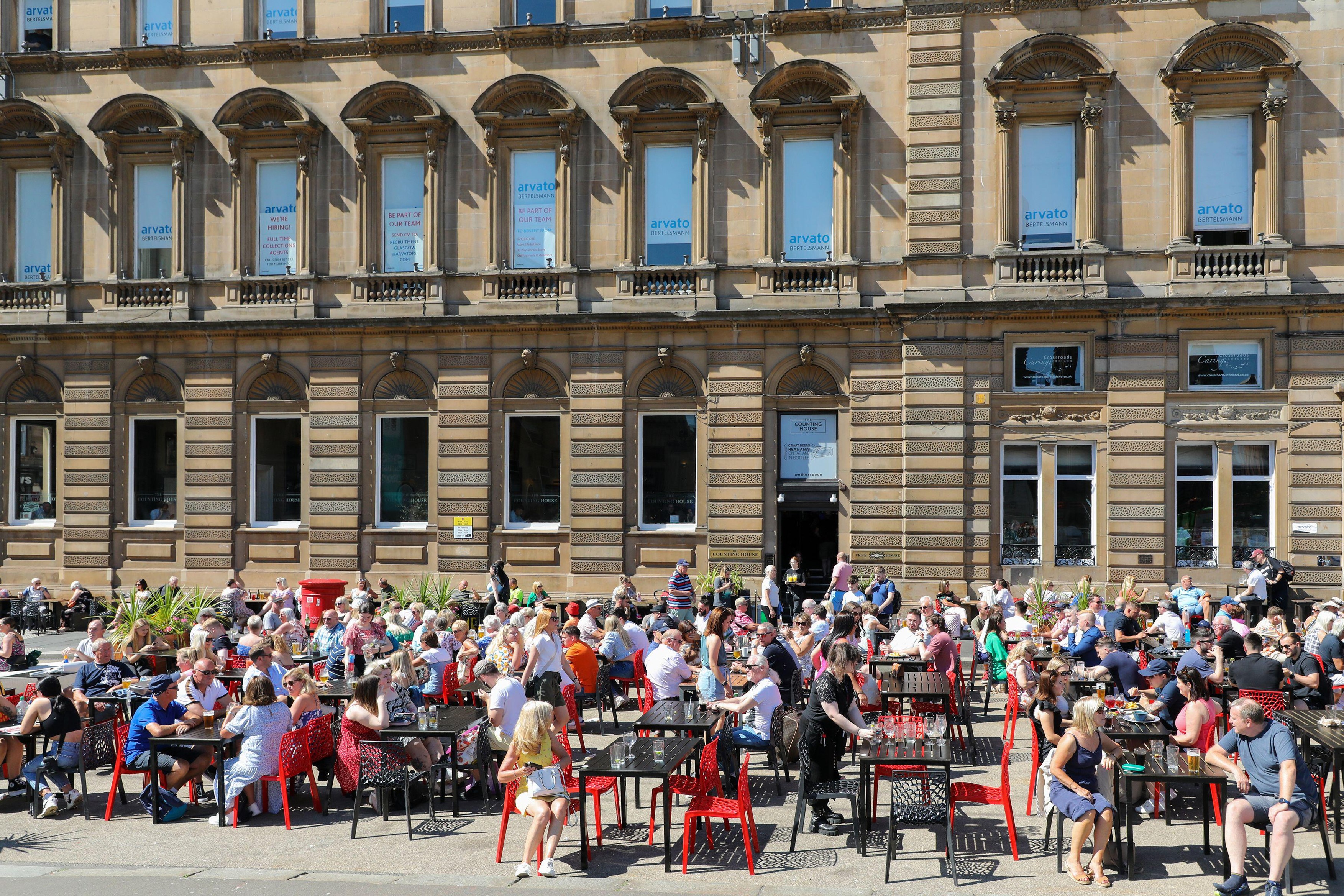 Glasgow, UK. 12th Aug, 2022. As summer temperatures reach 30c workers, tourists and locals take to George Square, bars and outdoor restaurants to enjoy the sunshine and relax. Credit: Findlay/Alamy Live News