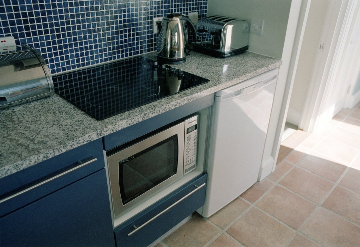 Picture shows modern appliances including a microwave electric hob toaster set in marble in the kitchen of new modern cottages