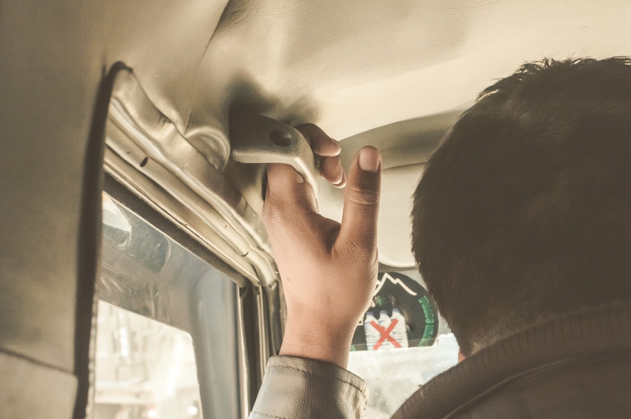 Hand on handle. A man holing a safety handel of a car along the highway journey Enjoying travel. Back view. Summer vacation concept with room for text