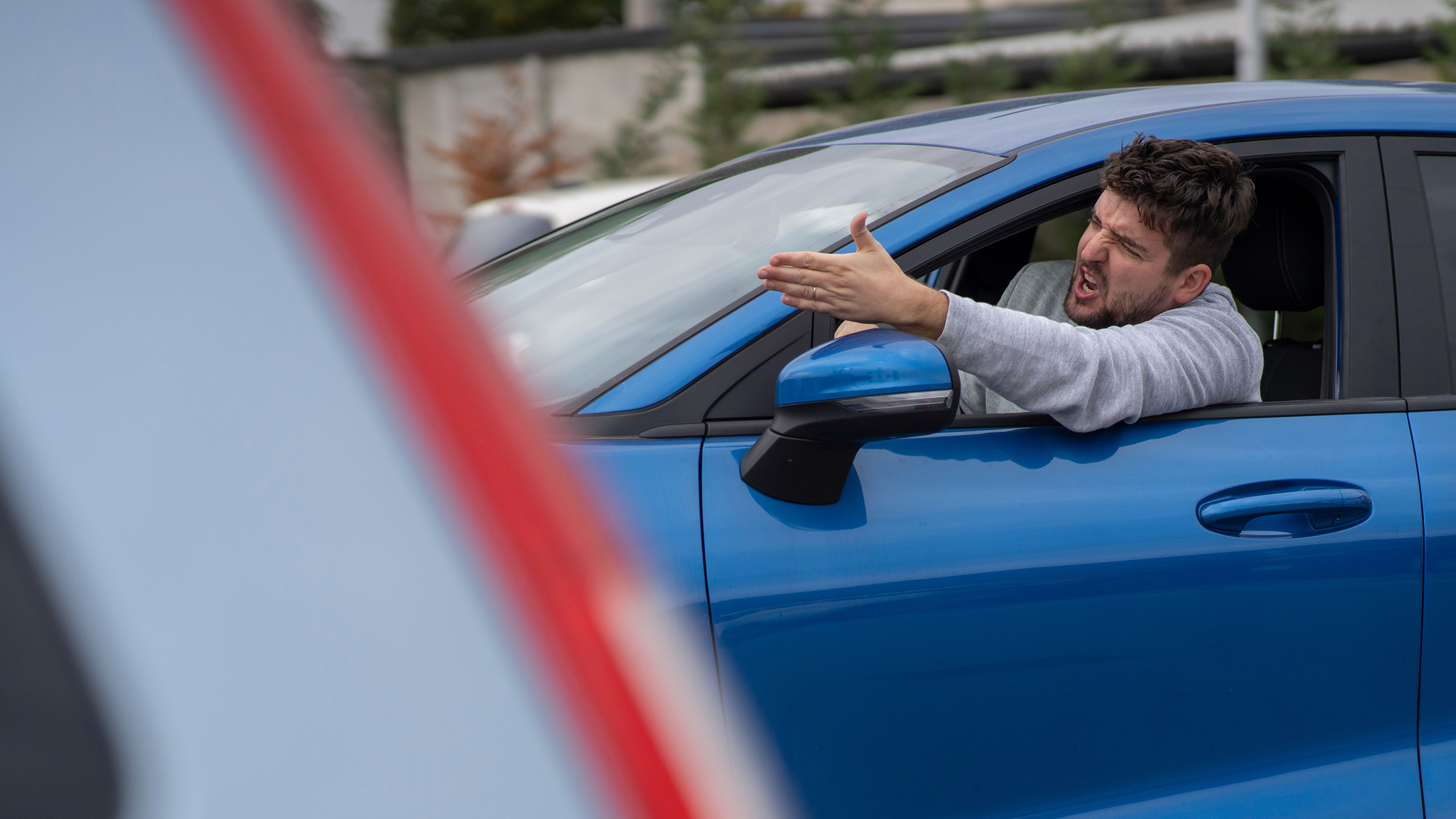 Angry man in the car in the queue yells at the driver in front. Side view Tagovi: svađa, saobraćaj, auto, nervoza, vožnja