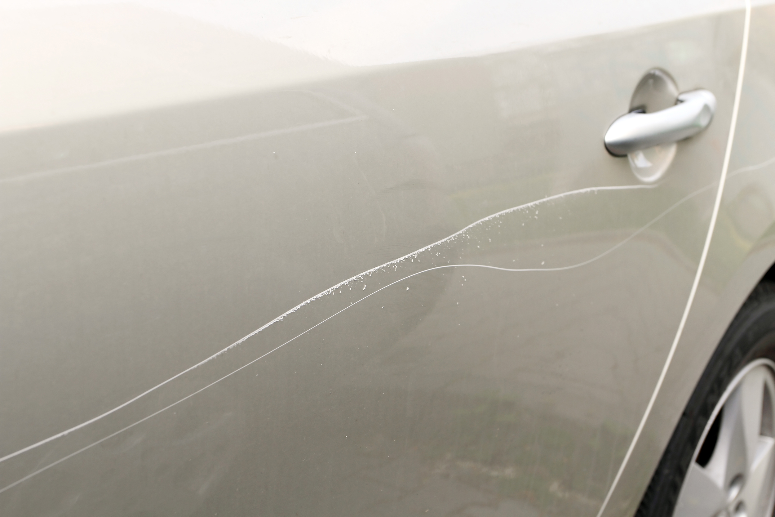 Scratched car paint with door handle and tire out of focus Tagovi: automobil, boja, ogrebotina