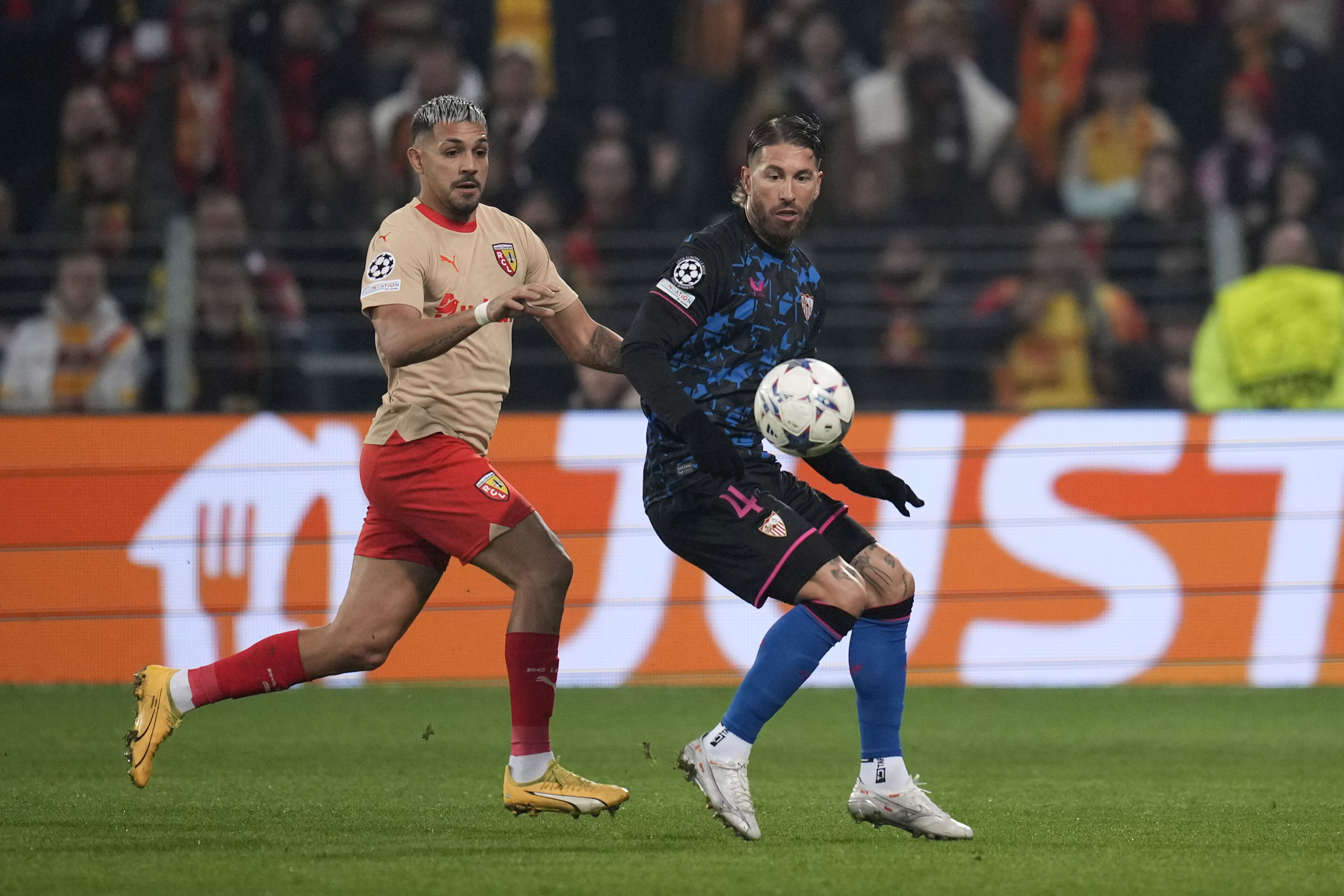 Lens' Facundo Medina, left, challenges for the ball with Sevilla's Sergio Ramos during the Champions League Group B soccer match between Lens and Sevilla at the Bollaert stadium in Lens, France, Tuesday, Dec. 12, 2023. (AP Photo/Thibault Camus)