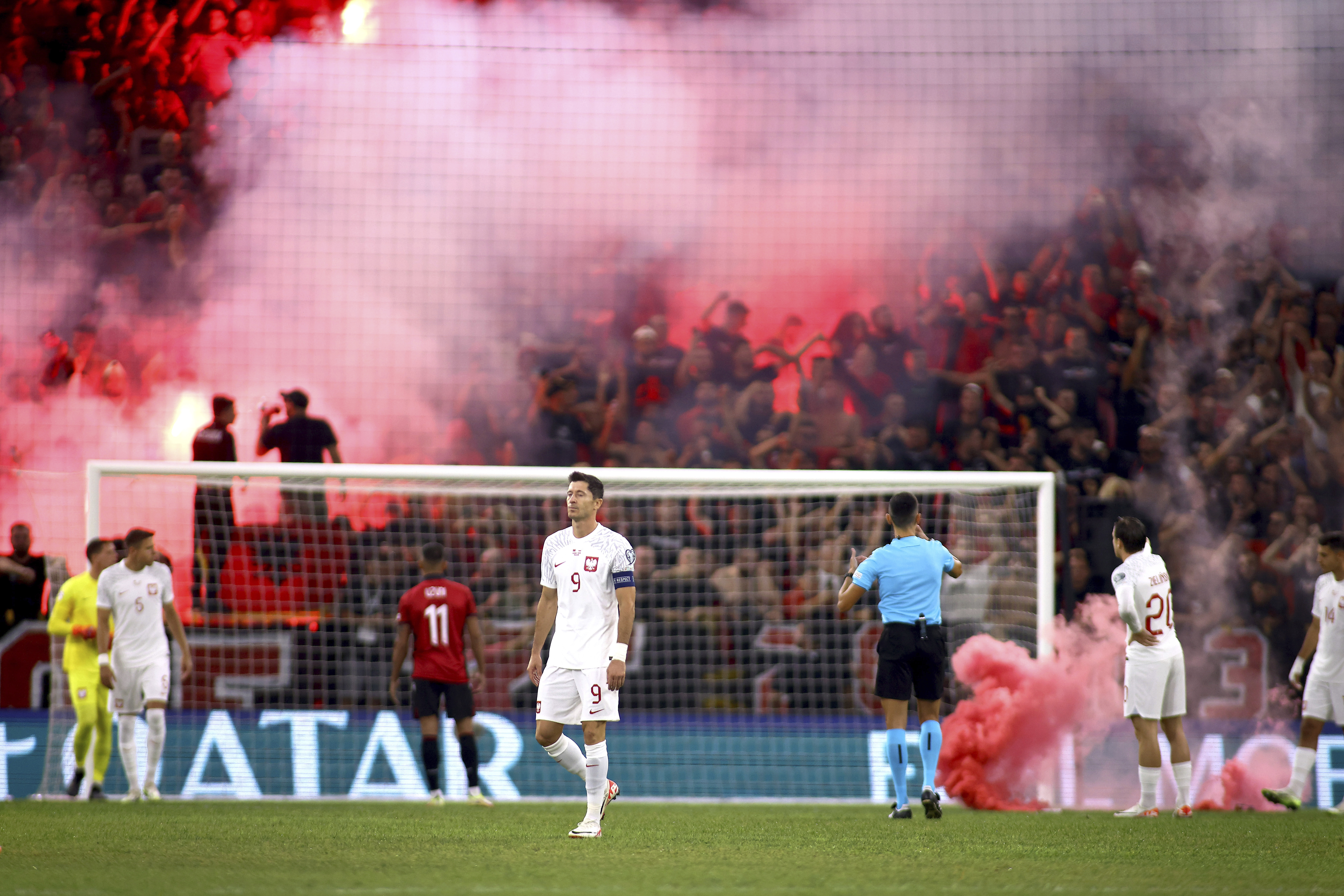 Poland's Robert Lewandowski, center, walks on the pitch while fireworks is lighted during the Euro 2024 group E qualifying soccer match between Albania and Poland in Tirana, Albania, Sunday, Sept. 10, 2023. (AP Photo/Franc Zhurda)