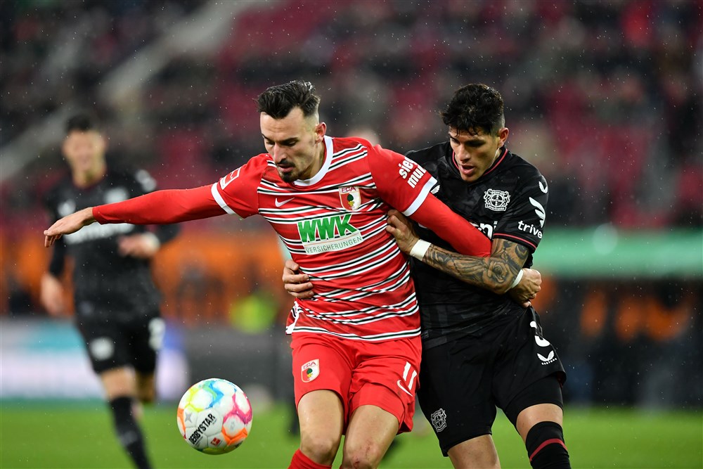 epa10446232 Augsburg's Mergim Berisha (L)  in action against Leverkusen's Piero Hincapie (R) during the German Bundesliga soccer match between FC Augsburg and Bayer 04 Leverkusen in Augsburg, Germany, 03 February 2023.  EPA-EFE/ANNA SZILAGYI