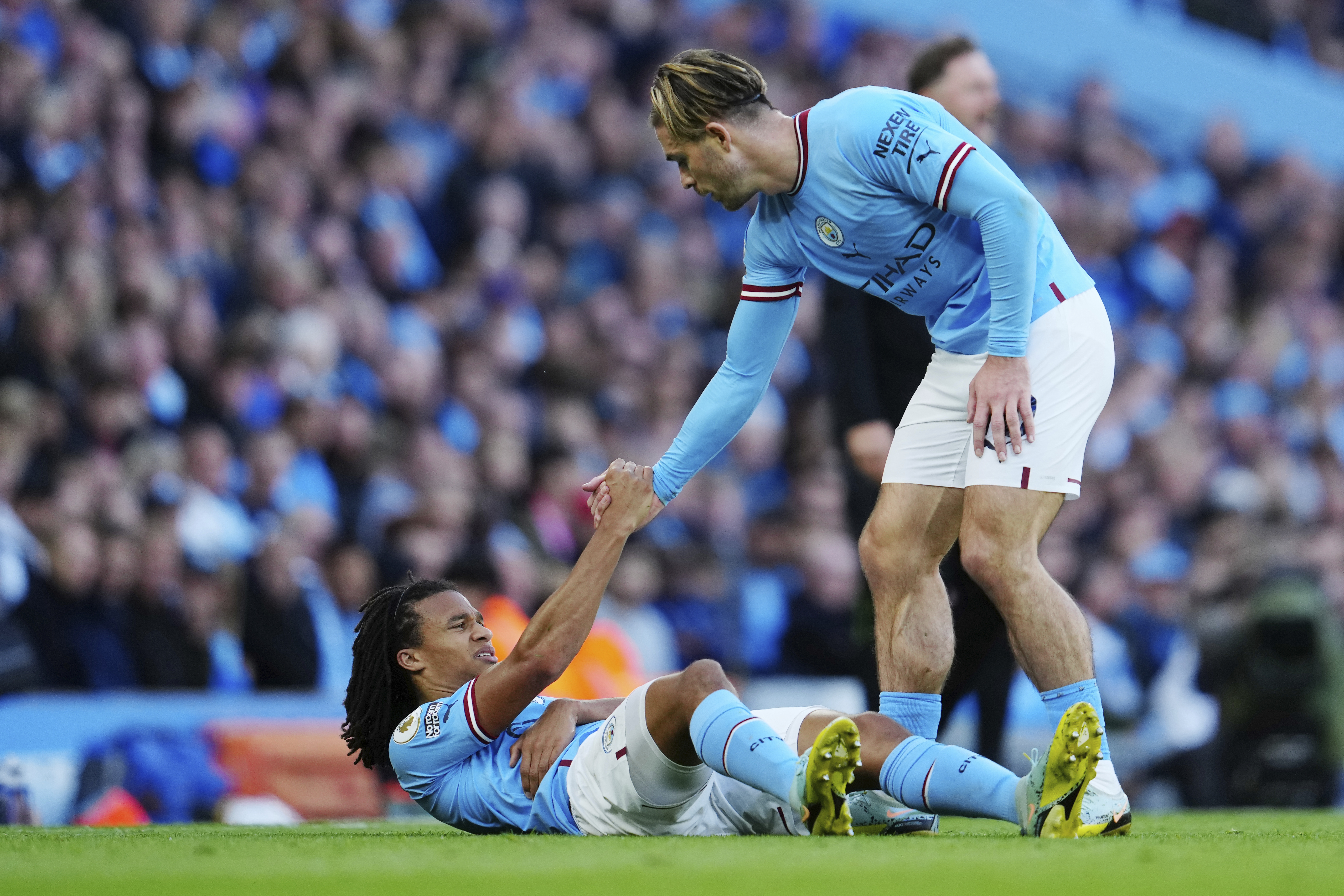 Manchester City's Jack Grealish, right, helps Nathan Ake to stand up during the English Premier League soccer match between Manchester City and Southampton at Etihad stadium in Manchester, England, Saturday, Oct. 8, 2022. (AP Photo/Jon Super)