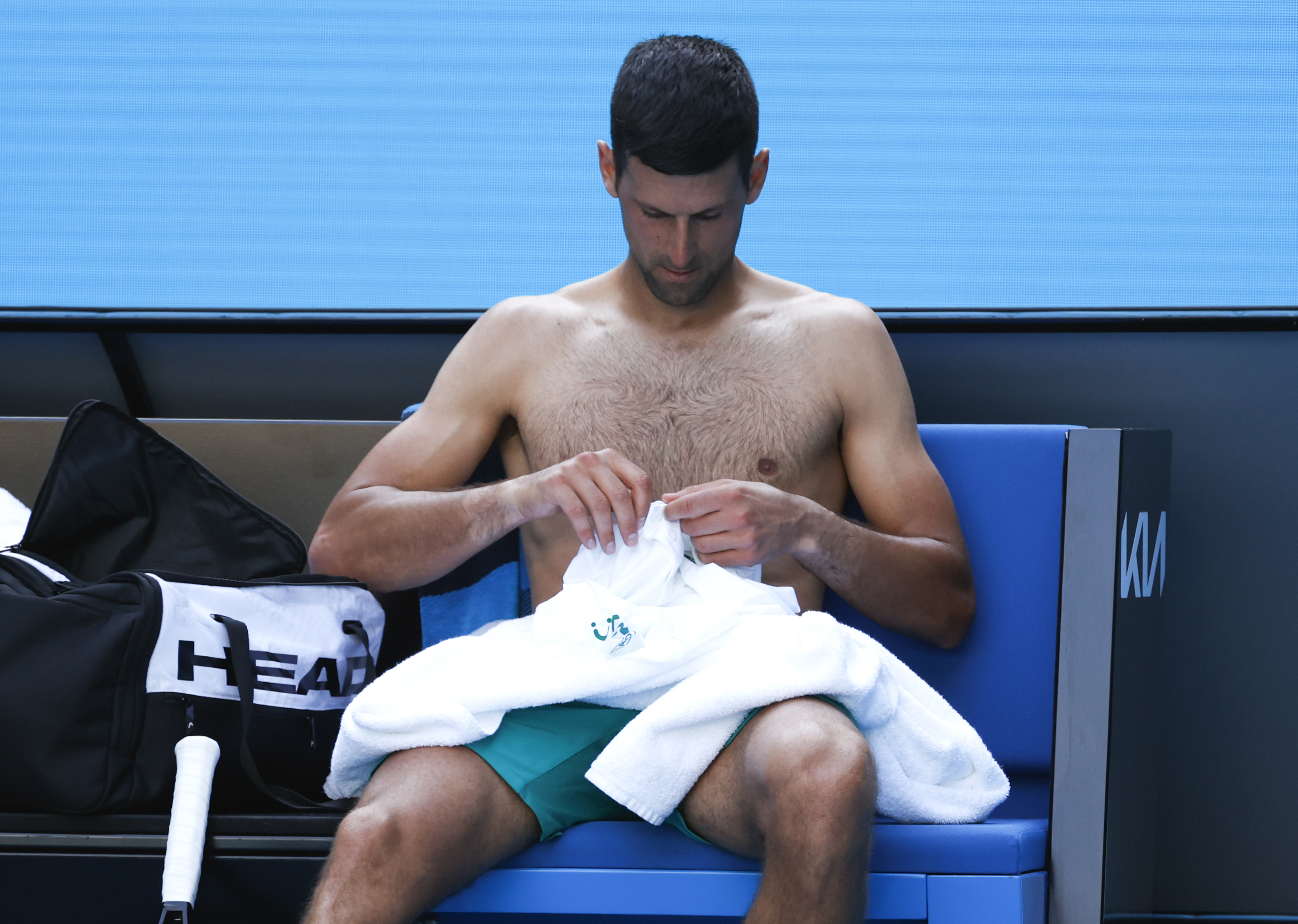 Serbia's Novak Djokovic prepares to change his shirt during his second round match against United States' Frances Tiafoe at the Australian Open tennis championship in Melbourne, Australia, Wednesday, Feb. 10, 2021.(AP Photo/Rick Rycroft)