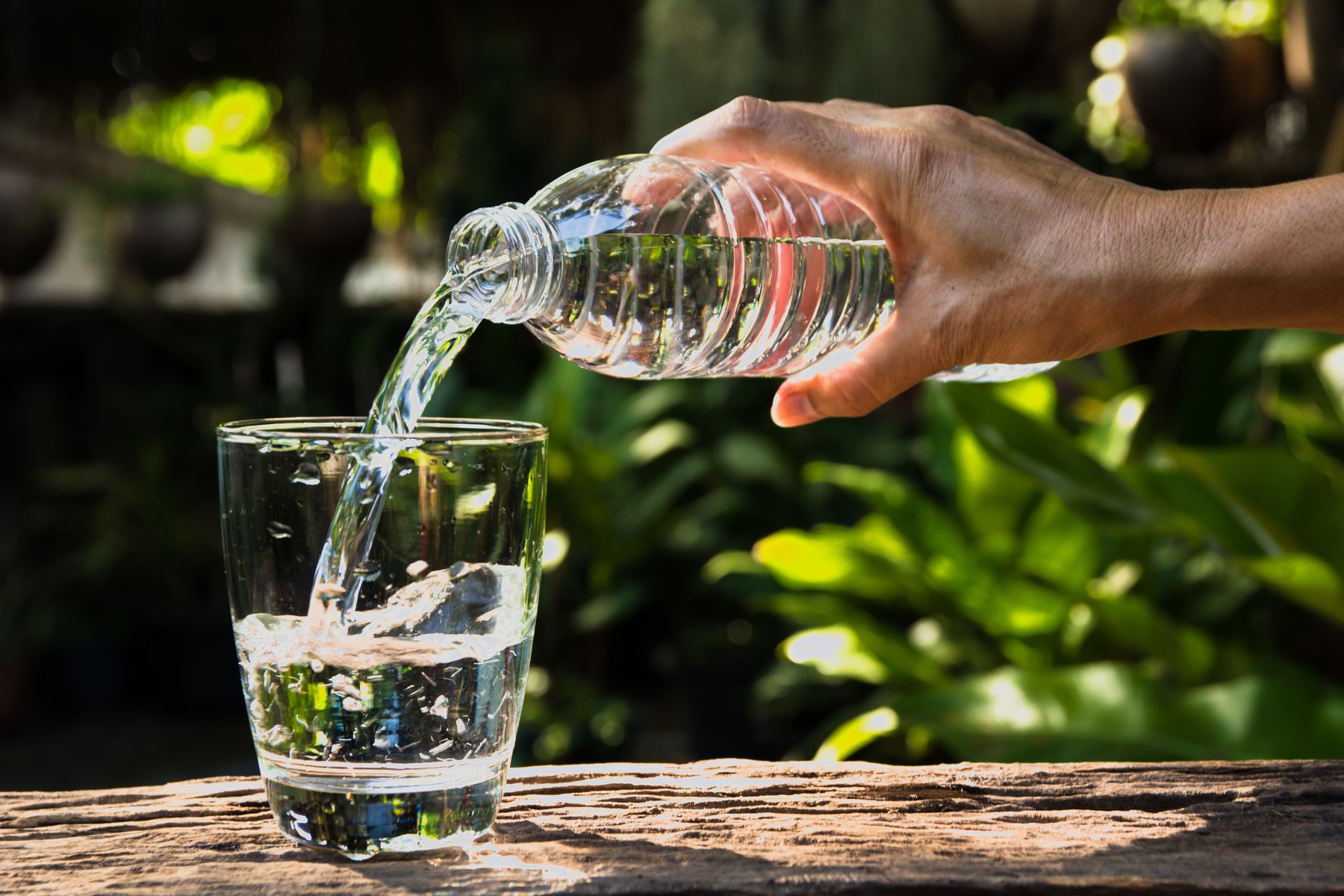 voda flaša  sipanje  Female hand pouring water from bottle to glass on nature background