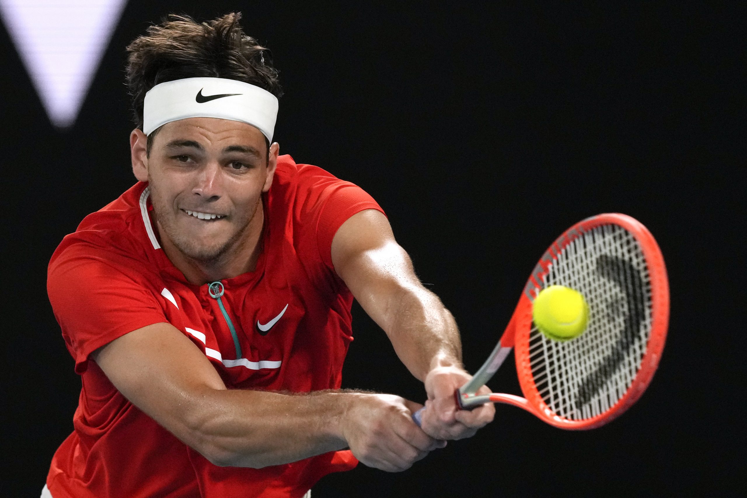 Taylor Fritz of the U.S. makes a backhand return to Stefanos Tsitsipas of Greece during their fourth round match at the Australian Open tennis championships in Melbourne, Australia, Monday, Jan. 24, 2022. (AP Photo/Simon Baker)
