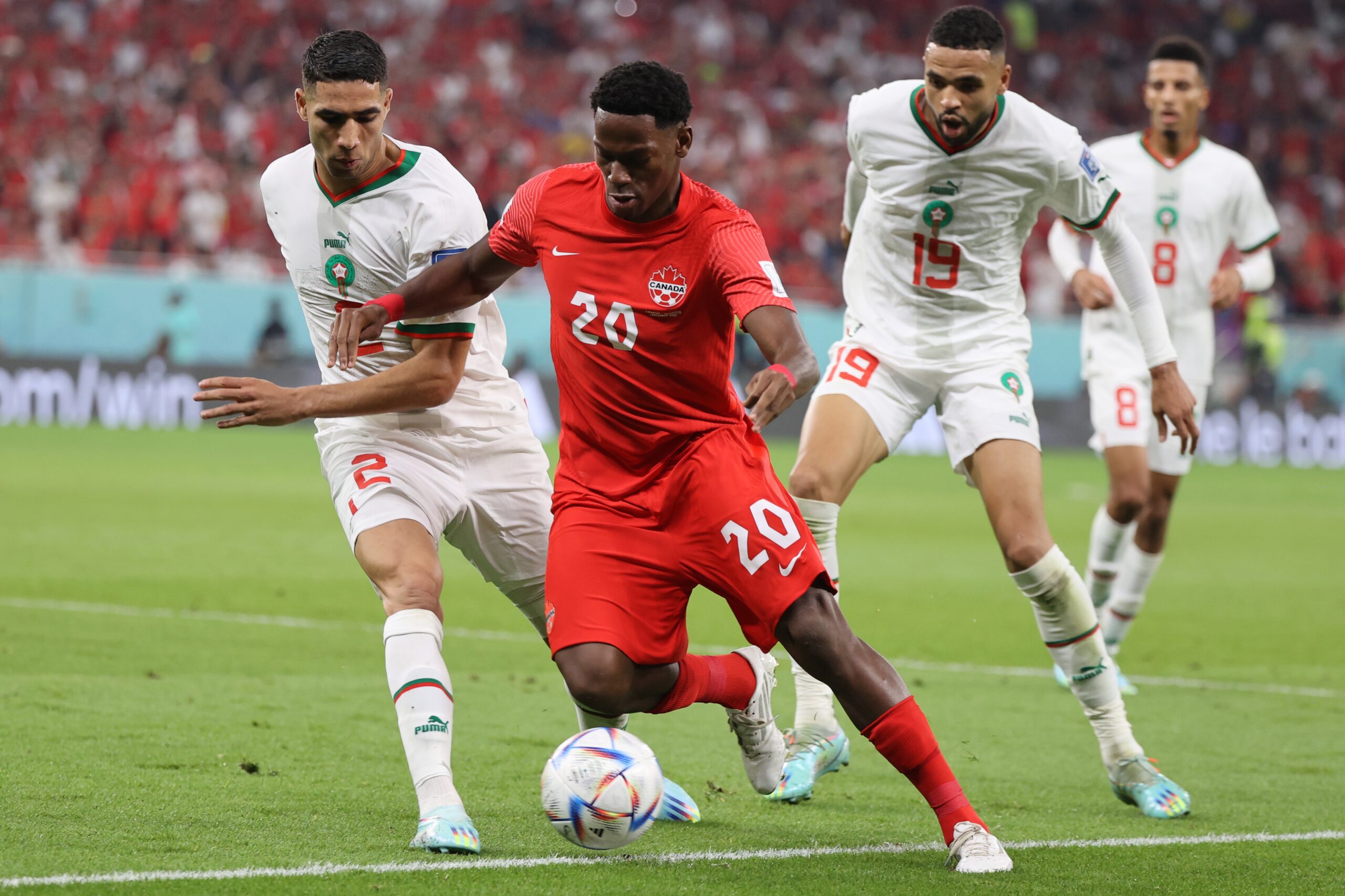 epa10341949 Jonathan David (2-L) of Canada in action against Achraf Hakimi of Morocco during the FIFA World Cup 2022 group F soccer match between Canada and Morocco at Al Thumama Stadium in Doha, Qatar, 01 December 2022.  EPA-EFE/Mohamed Messara