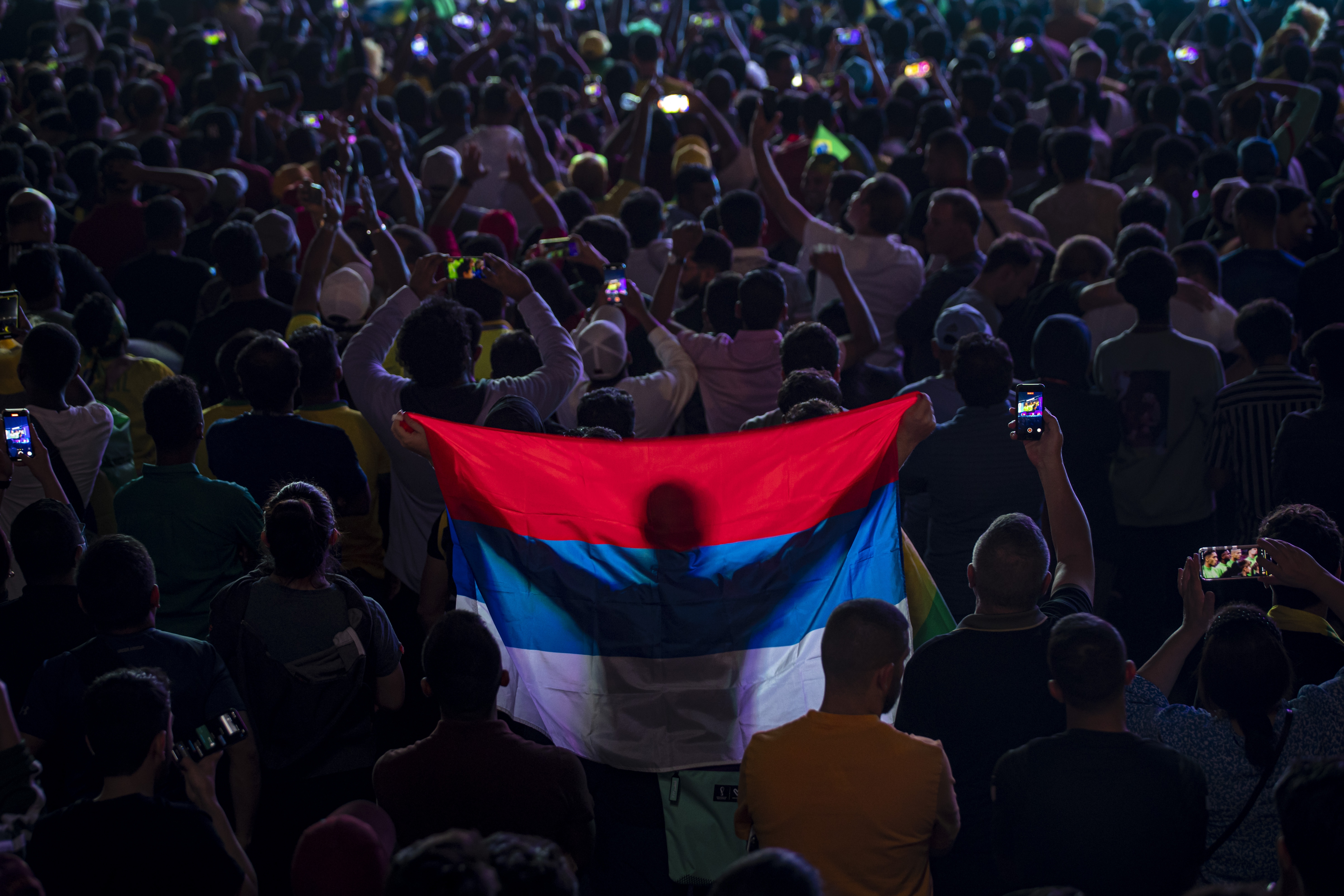 epaselect epa10326132 A fan holds the Serbian flag as people watch the FIFA World Cup Qatar 2022 match between Brazil and Serbia at the Fan Festival in the centre of Doha, Qatar, 24 November 2022.  EPA-EFE/MARTIN DIVISEK