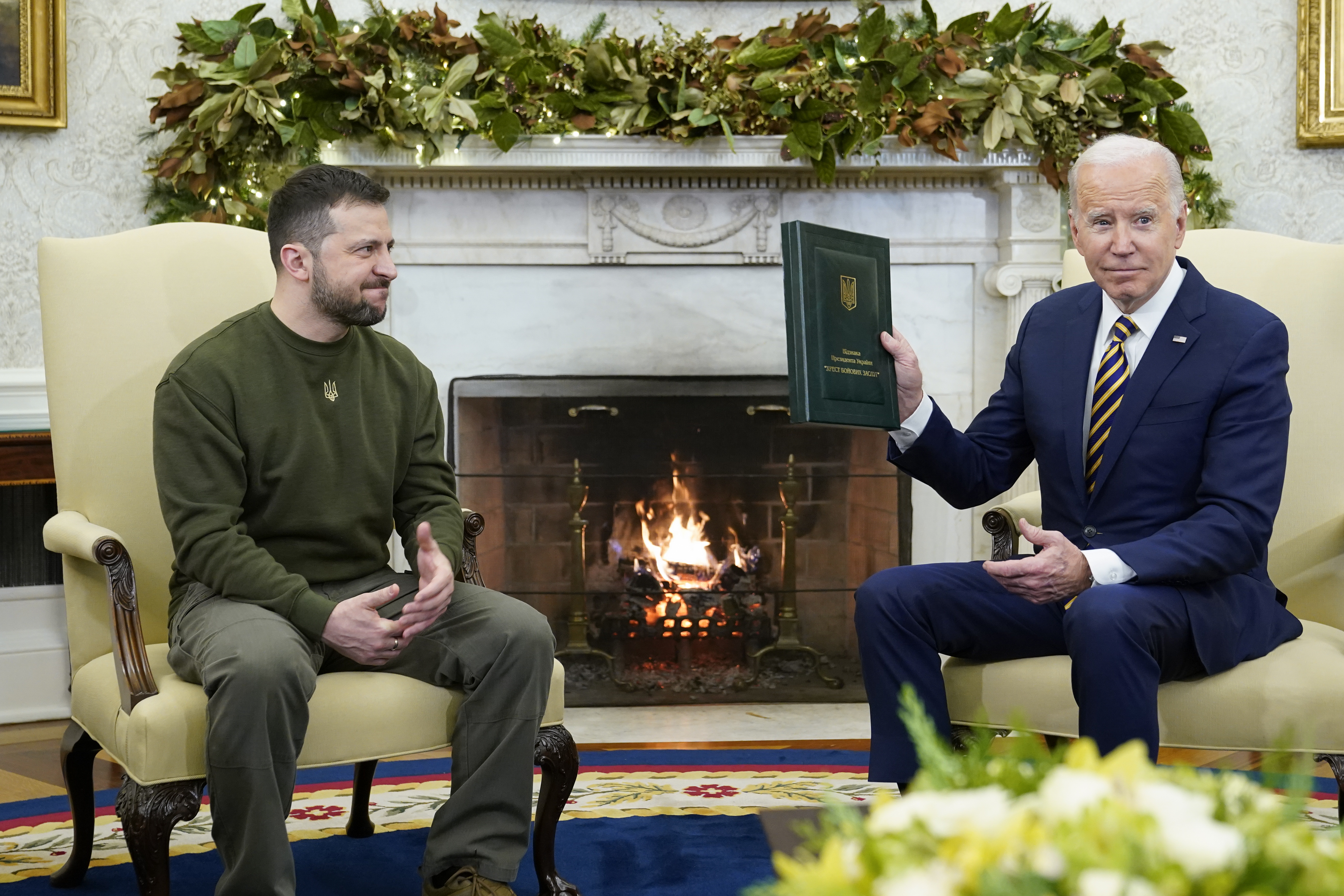 President Joe Biden holds a gift he received from Ukrainian President Volodymyr Zelenskyy as they meet in the Oval Office of the White House, Wednesday, Dec. 21, 2022, in Washington. (AP Photo/Patrick Semansky)