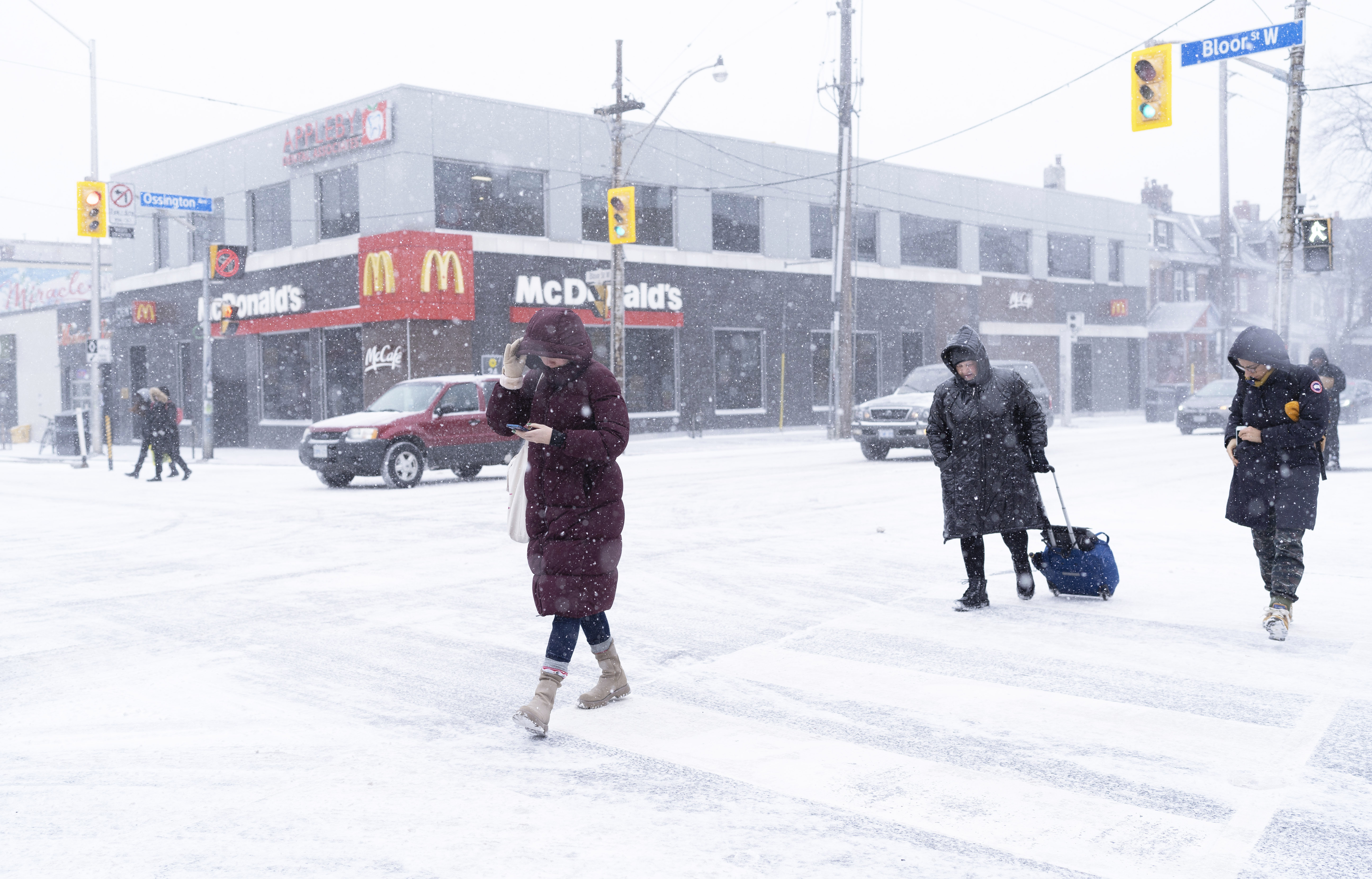 People cross Bloor Street during a snowstorm in Toronto on Friday, Dec. 23, 2022. A winter storm warning is in place for most of southern Ontario. (Arlyn McAdorey /The Canadian Press via AP)