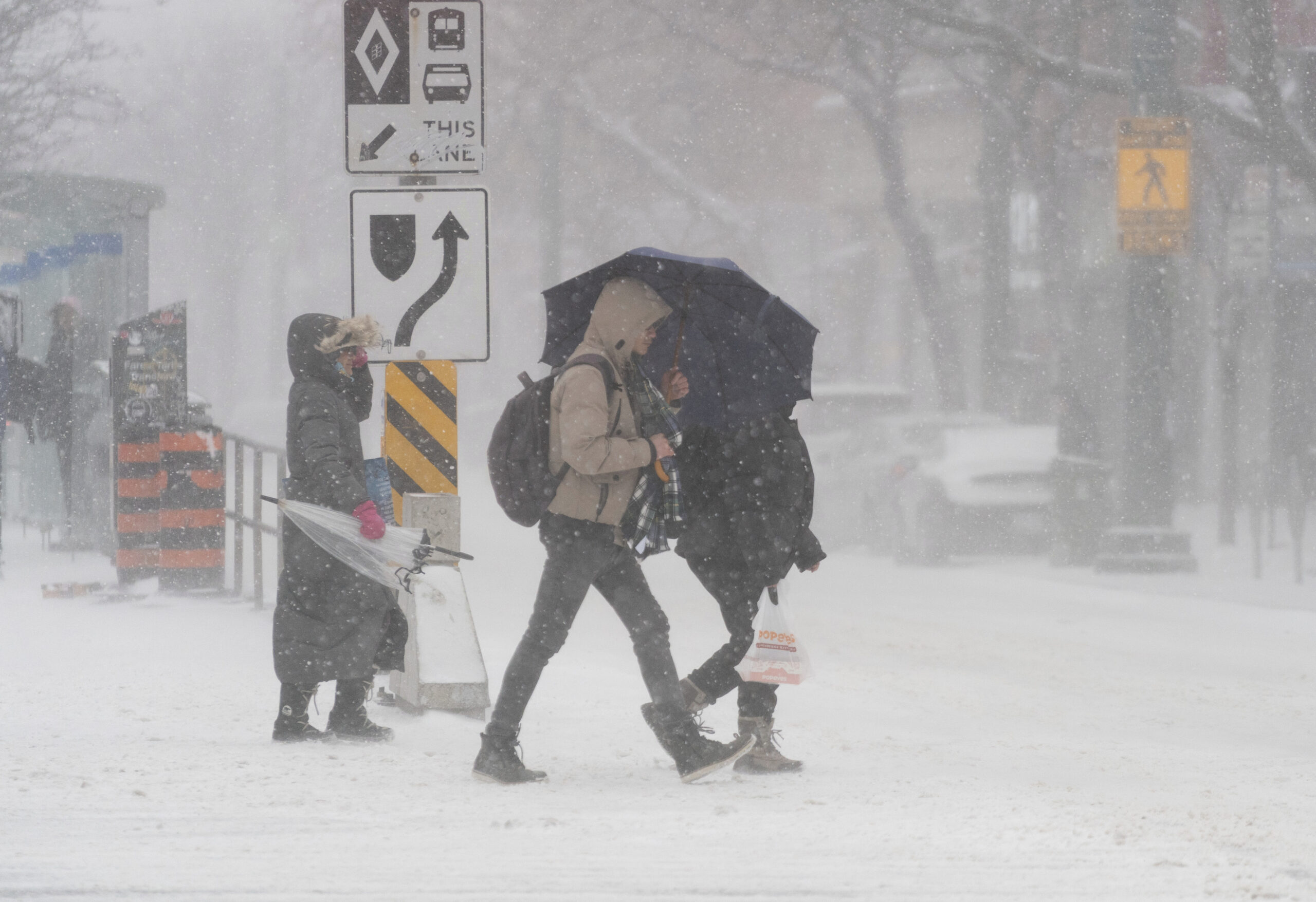 Transit riders face blowing snow after leaving a streetcar stop during a snowstorm in Toronto on Friday, Dec., 23, 2022. A winter storm warning is in place for most of southern Ontario. (Arlyn McAdorey/The Canadian Press via AP)
