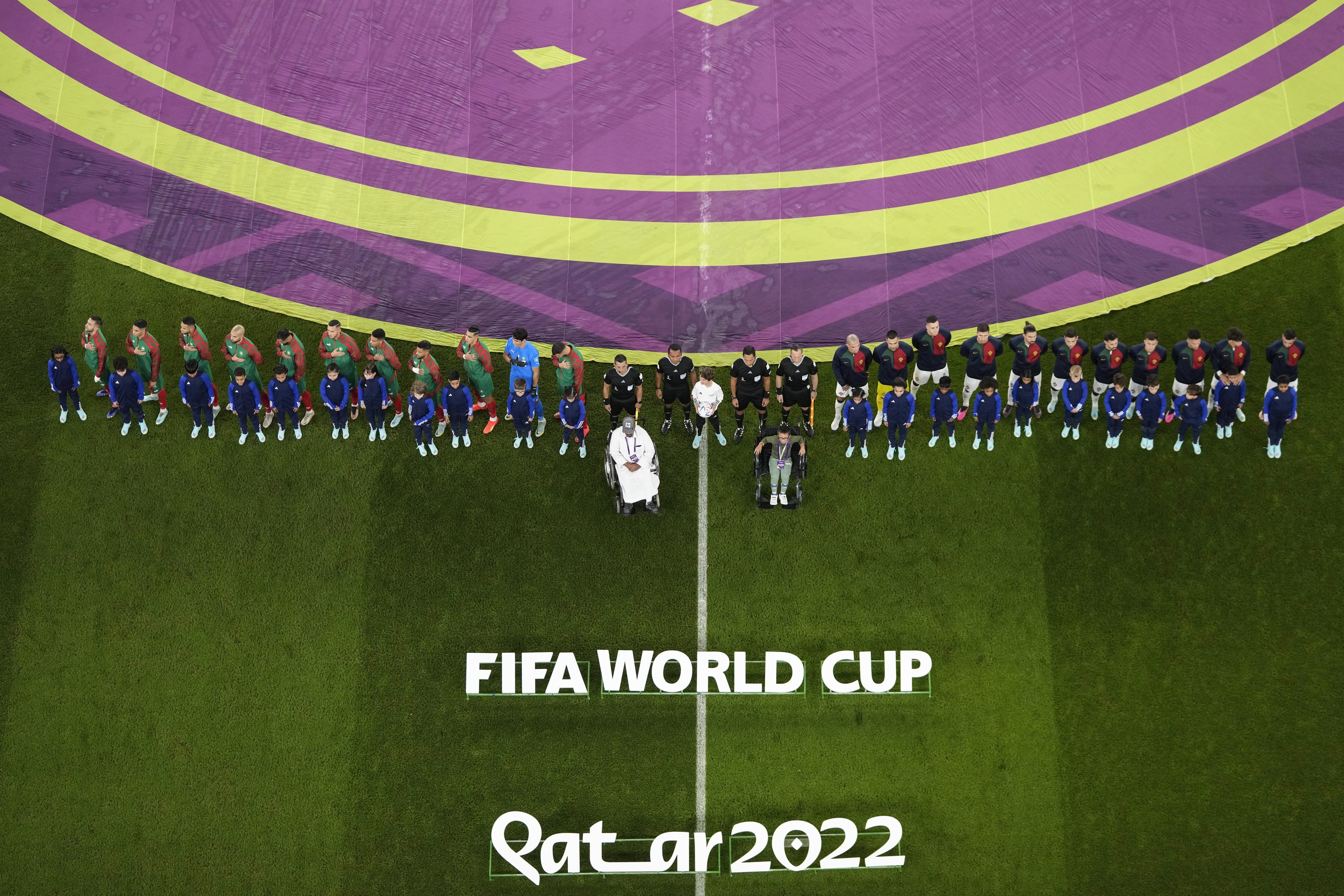 The teams of Morocco, left, and Portugal listen the national anthem prior the start of the World Cup quarterfinal soccer match between Morocco and Portugal, at Al Thumama Stadium in Doha, Qatar, Saturday, Dec. 10, 2022. (AP Photo/Thanassis Stavrakis)