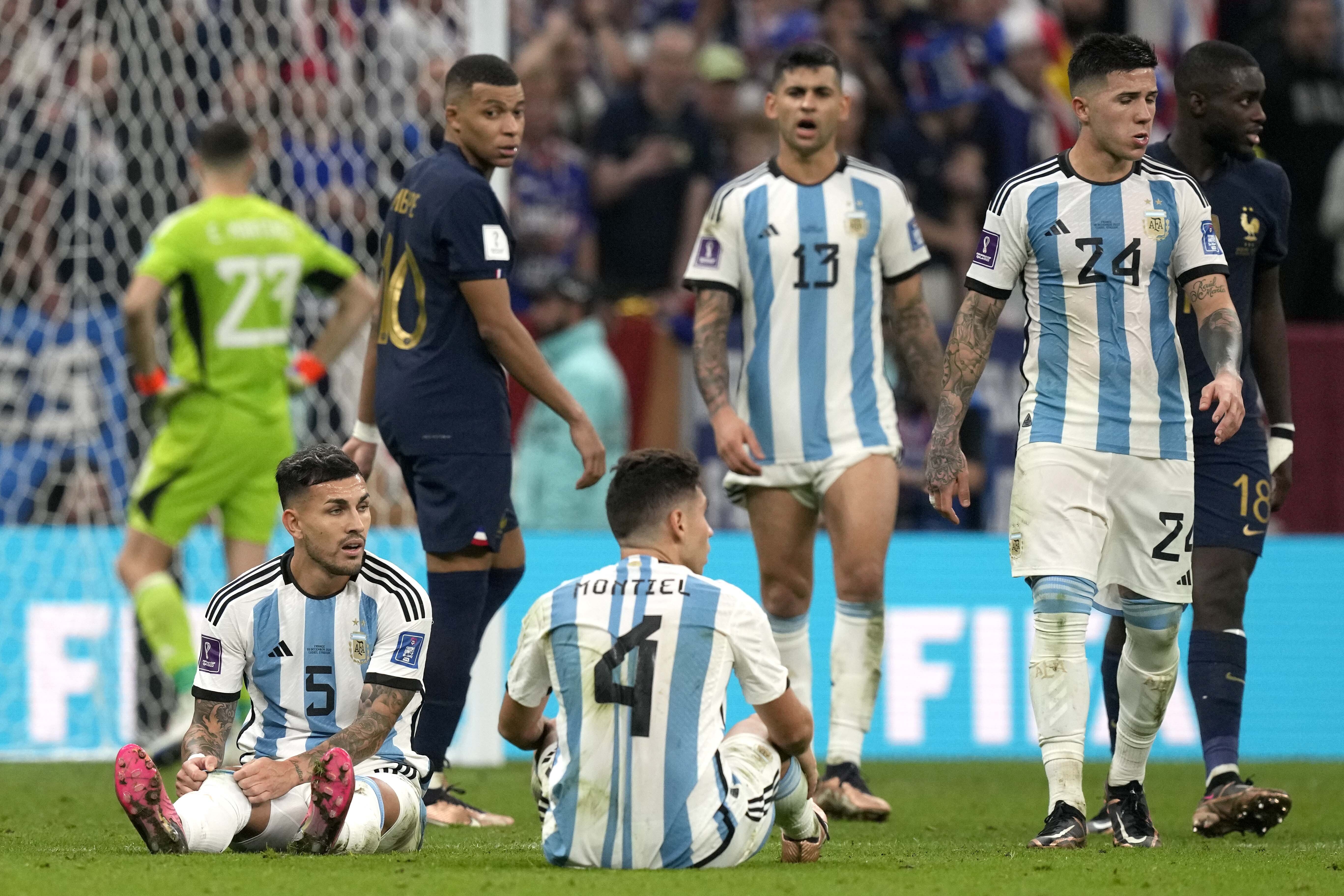 Argentina's Leandro Paredes, left, and Argentina's Gonzalo Montiel sit on the ground during the World Cup final soccer match between Argentina and France at the Lusail Stadium in Lusail, Qatar, Sunday, Dec. 18, 2022. (AP Photo/Frank Augstein)