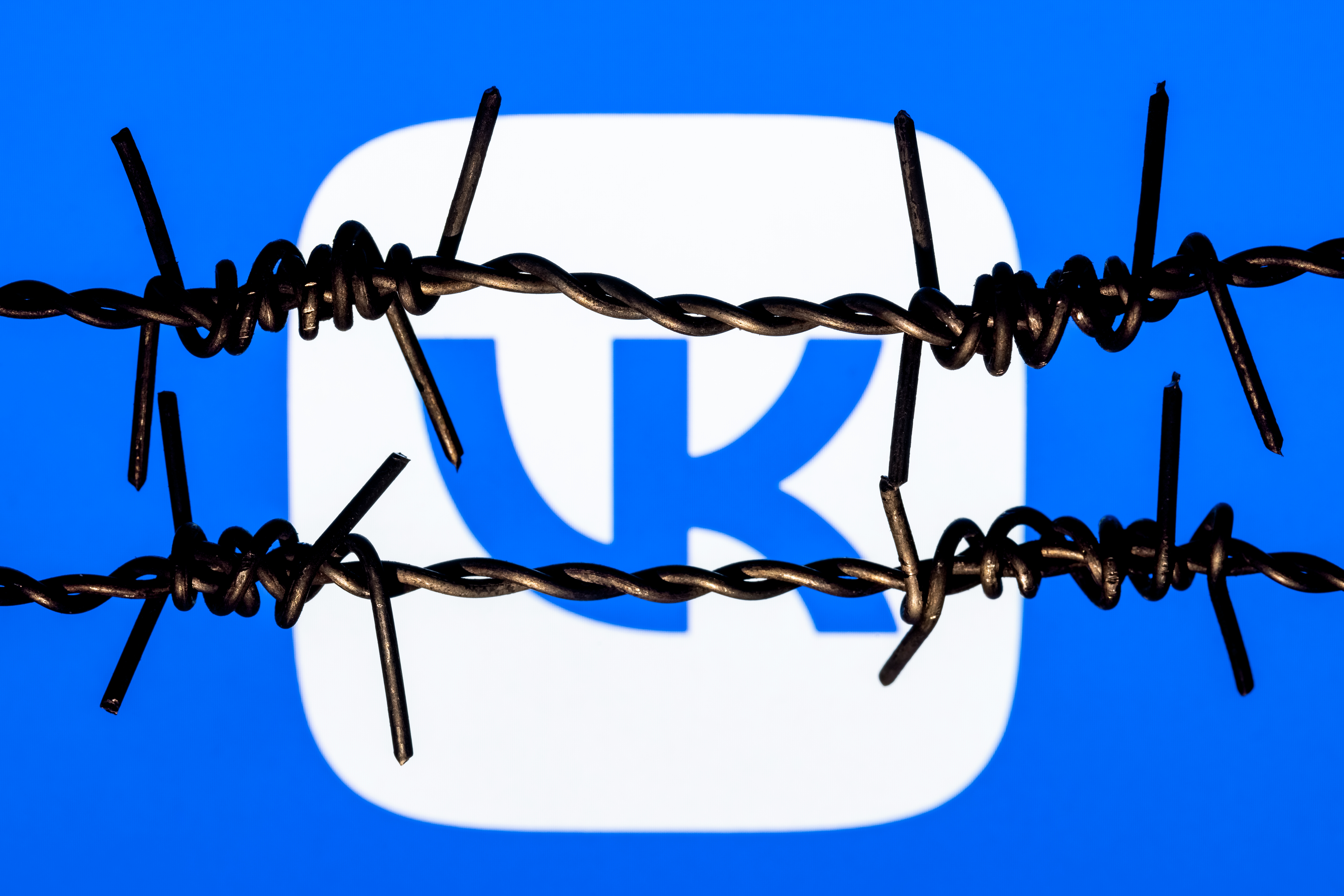 Kazan, Russia - Nov 13, 2021: VKontakte social network logo behind barbed wire. The concept of VKontakte censorship and prohibition. VK
